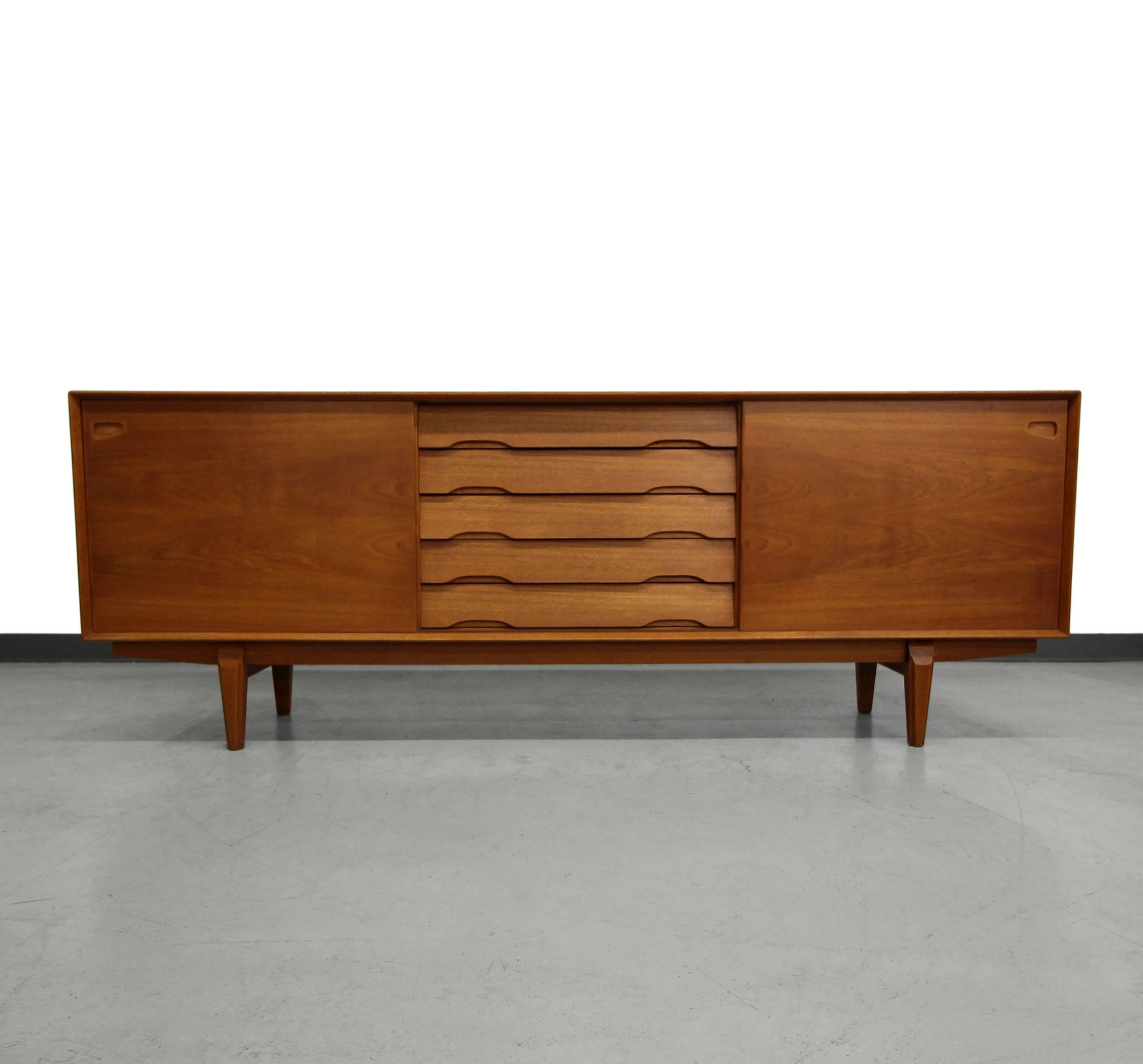 Measuring in at over 7 feet, this is a long, beautiful midcentury Danish teak credenza by Rosengren Hansen. A high quality, heavy piece with gorgeous solid teak edges and legs. Credenza features five staggered centre drawers that create dimensional