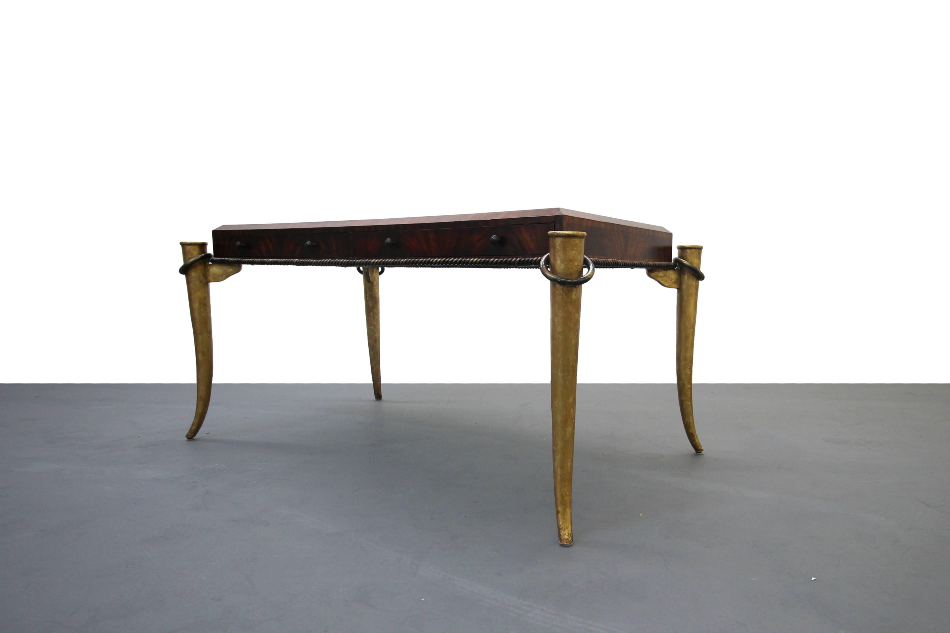 This is an absolutely stunning example of Maitland Smith's finest work. This desk features an amazingly bookmatched mahogany top laid out in the most striking pattern, resting on solid metal tusk legs finished in beautiful gold gilt, it is finished