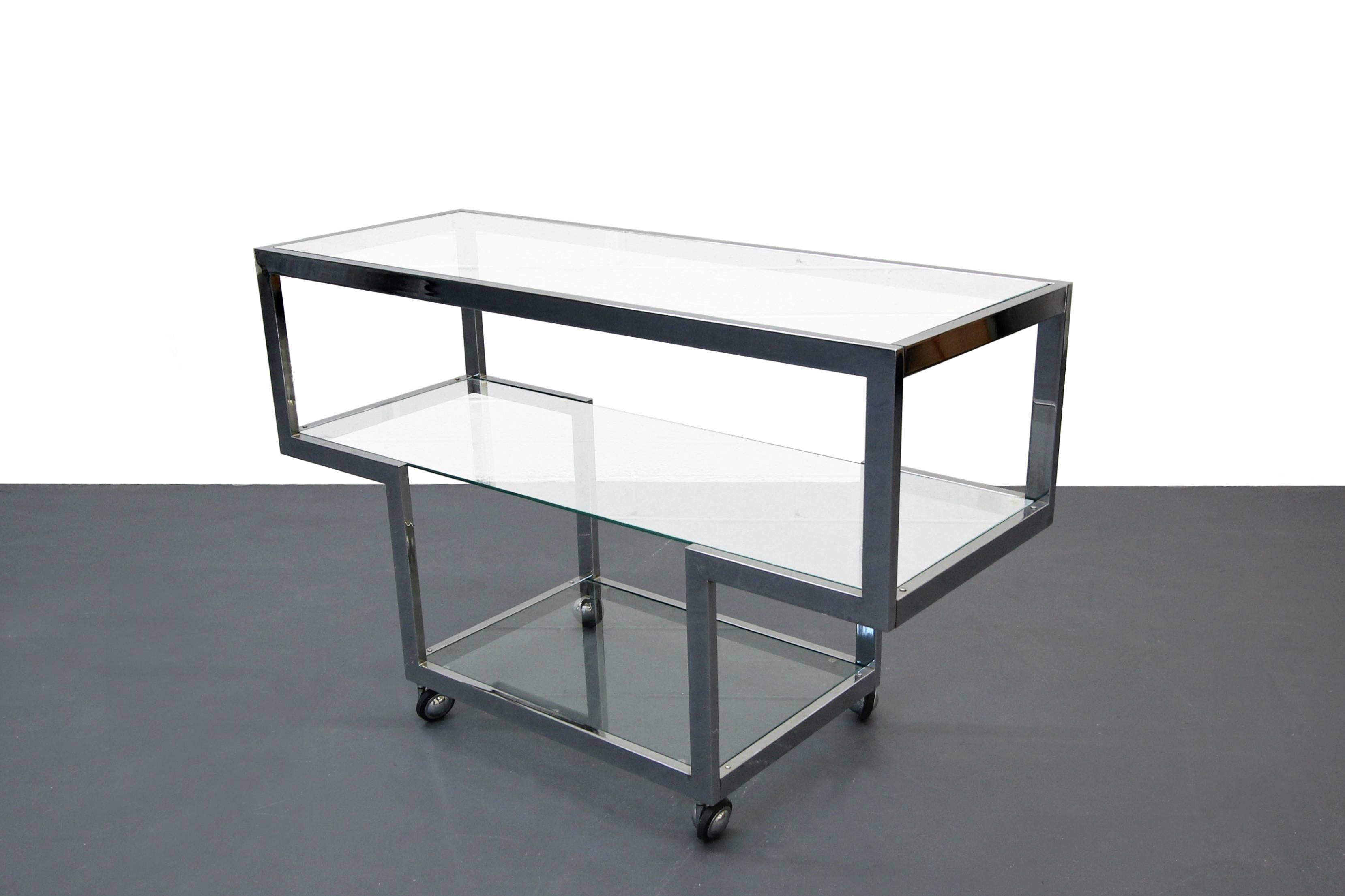 Simplistic yet sophisticated chrome and glass Mid-Century bar cart by Milo Baughman. The transparency of this piece makes it perfect in most any space. With three tiers of glass shelving for all your display and storage needs.

Cart is in excellent
