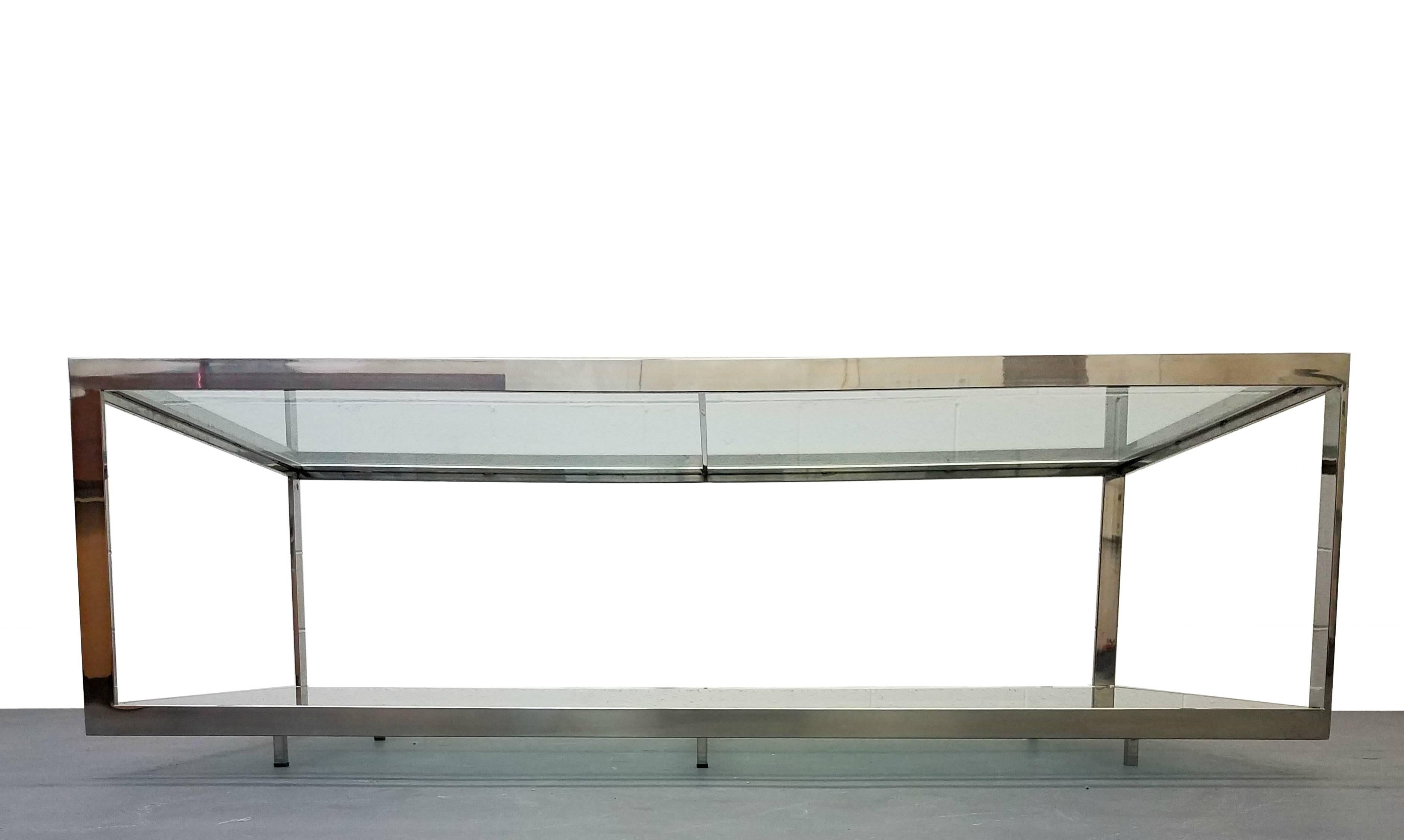 This is an extremely large and versatile chrome and glass, midcentury coffee table. The table frame features a unique divided look that supports the two levels of glass. The coffee table also has six small legs. Perfect for the person who wants to