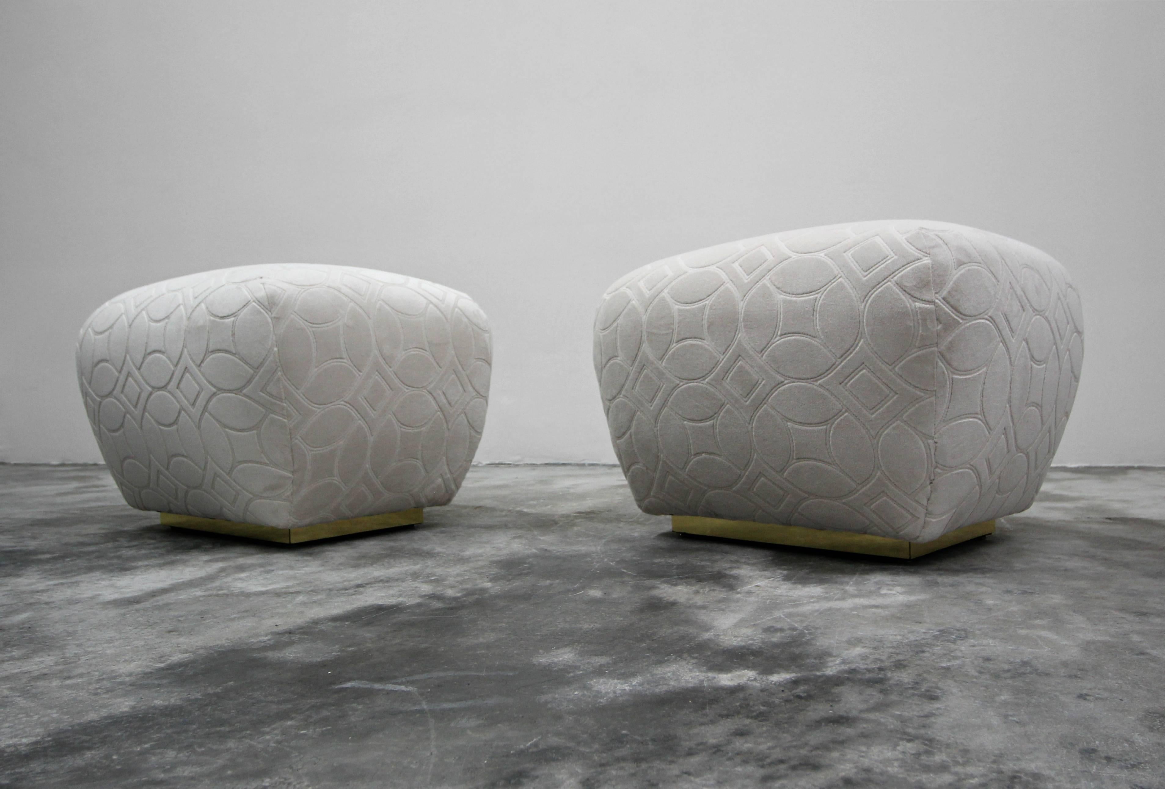 Pair of brass base Souffle ottomans poufs. Professionally reupholstered in a patterned and textured vanilla color velvet. Brass is in excellent condition with little to no tarnish or patina.