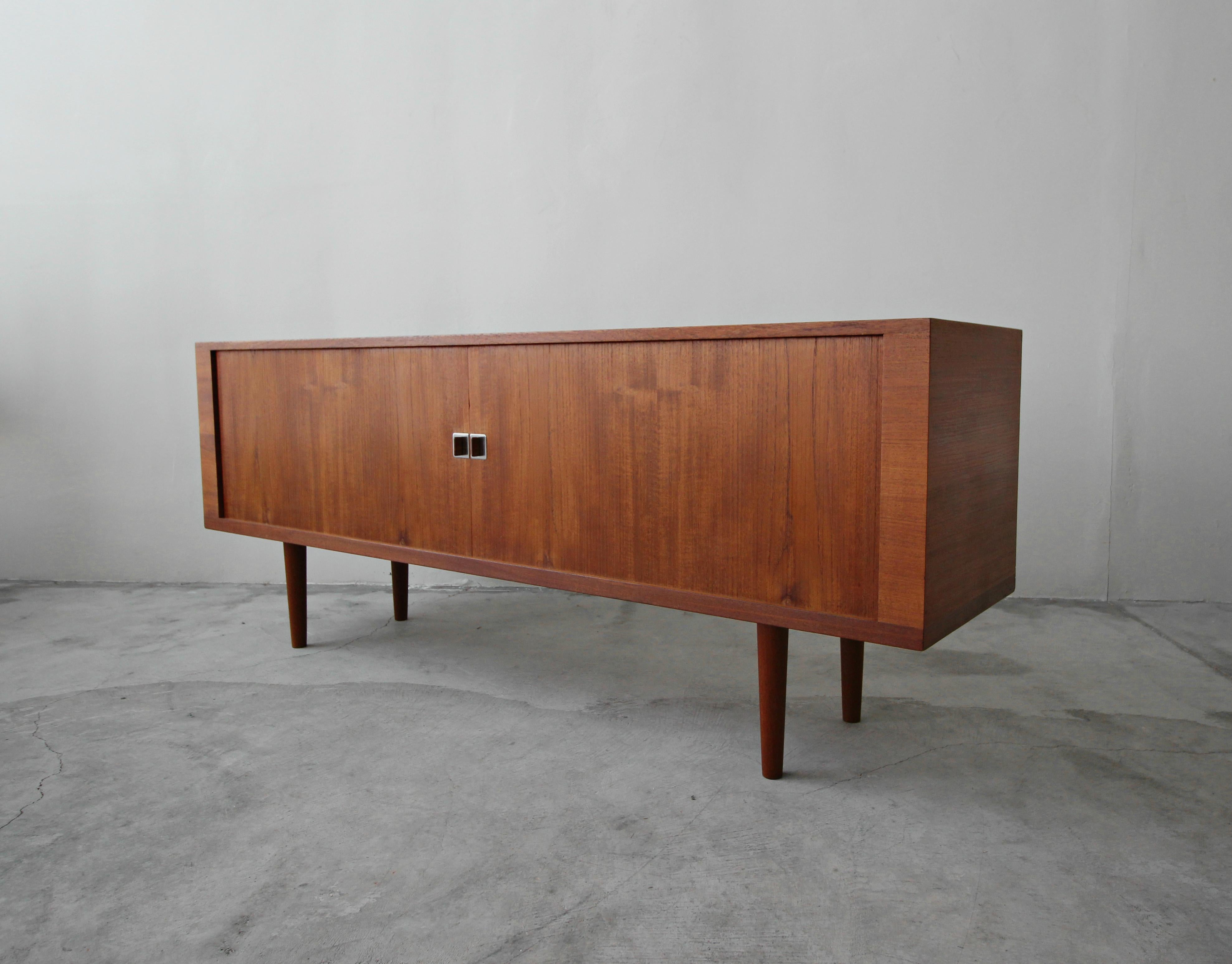 The president credenza by Hans Wegner for Ry Mobler is a Danish classic. Features beautiful teak graining, unique teak and chrome pulls and sliding tambour doors. Behind the tambours are 3 compartments, 2 with 2 shelves each and a centre section