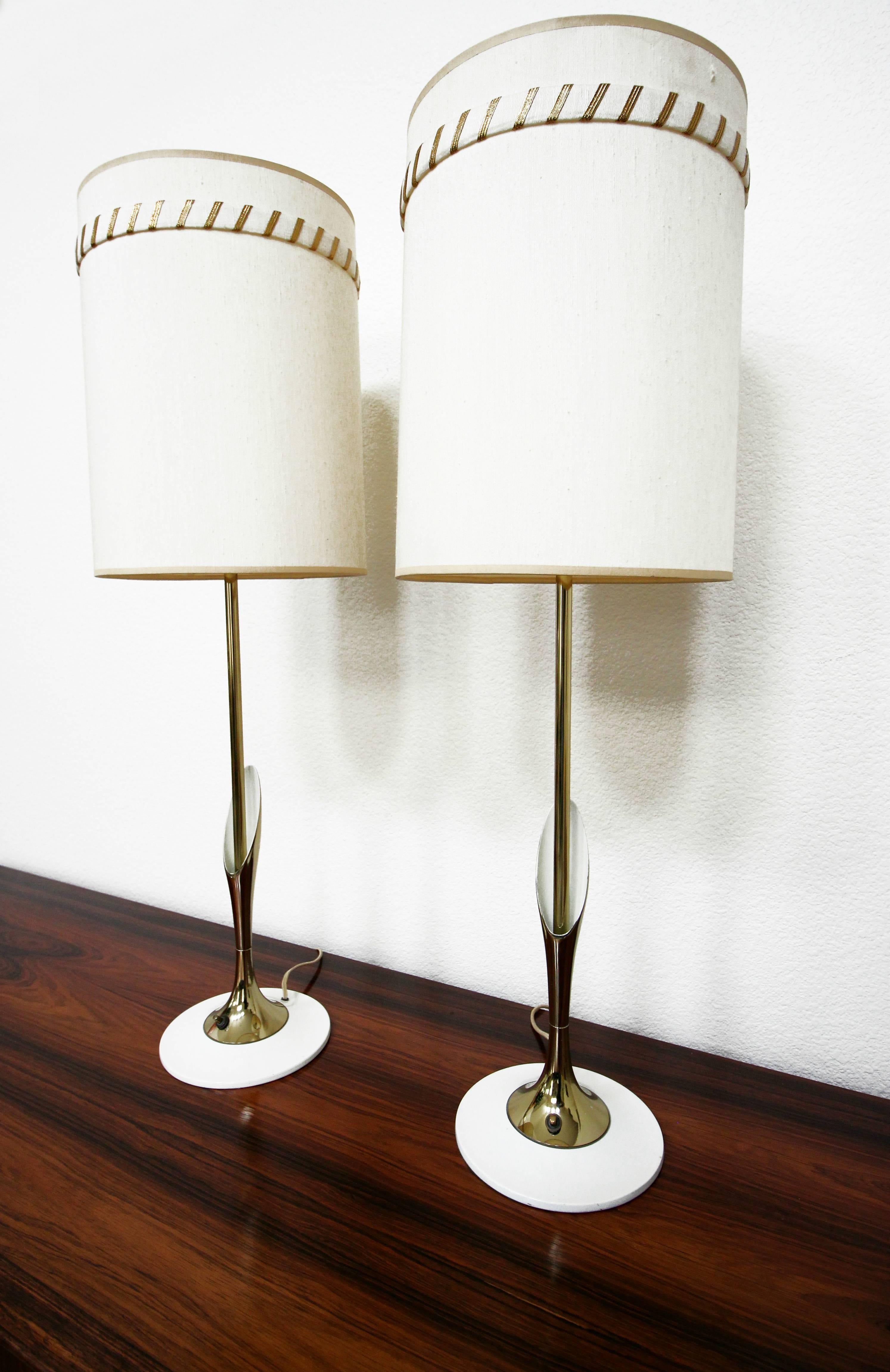 These are a super sleek and slender pair of Mid-Century Modern sculptural brass lamps by Laurel Lamp Company. They have a thin brass stem with a beautiful brass lily style detail and a unique thin white enameled base. 

The lamps are pictured with