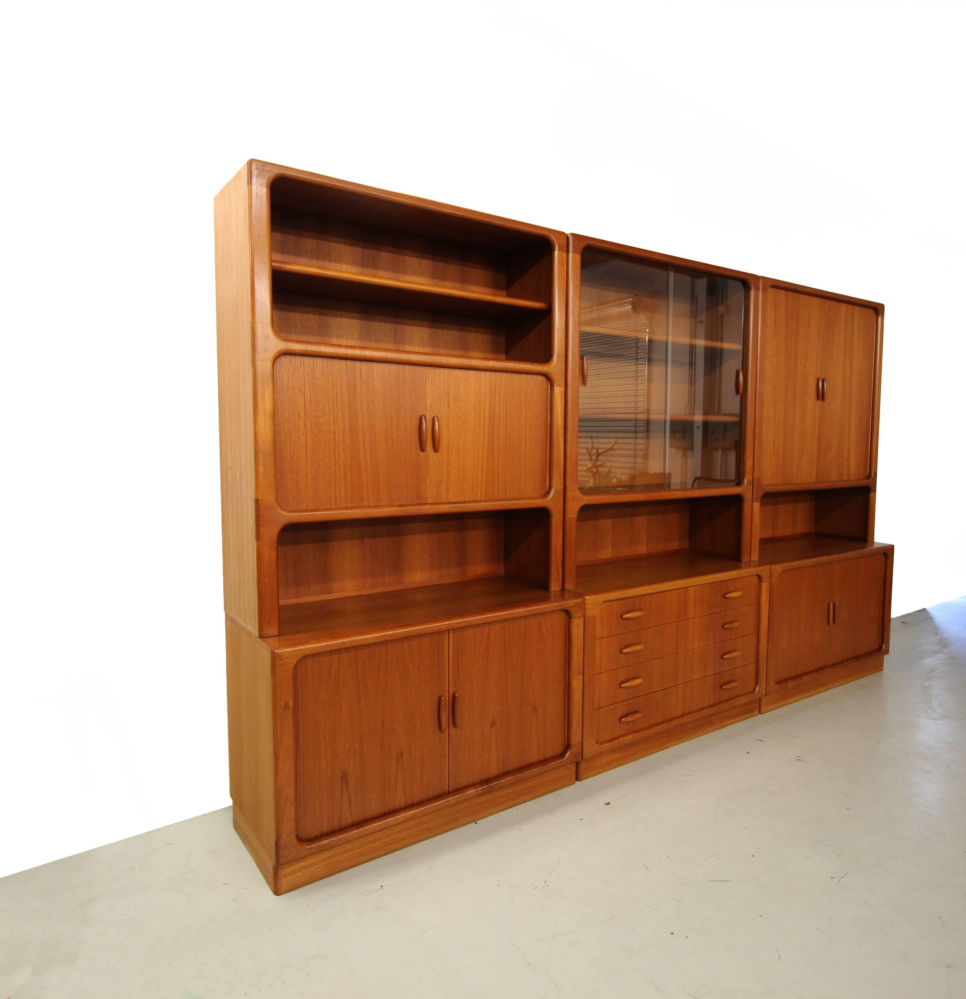 This a substantial set of 3 Danish Teak Wall Units by Dyrlund. Each wall unit is comprised of a top and a bottom piece that may be used separately or all together as shown. This is the perfect unit for someone looking for a bookcase or ample