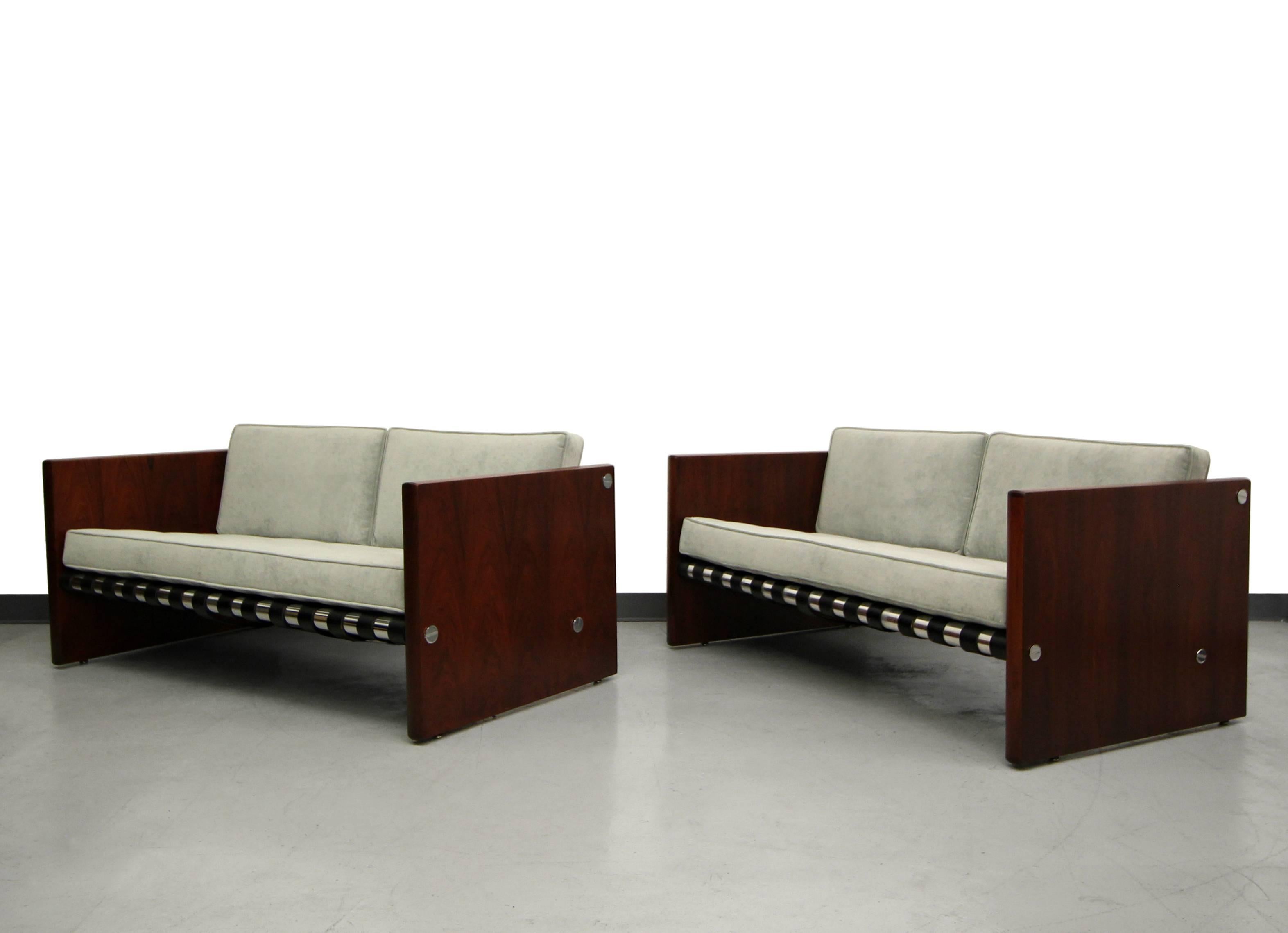 Absolutely perfect duo. A pair of Mid-Century Danish rosewood and chrome sling sofas. Sofas feature rosewood slab sides with three chrome rails that support a set of leather straps that create a sling for the cushions. These sofas have a beautiful