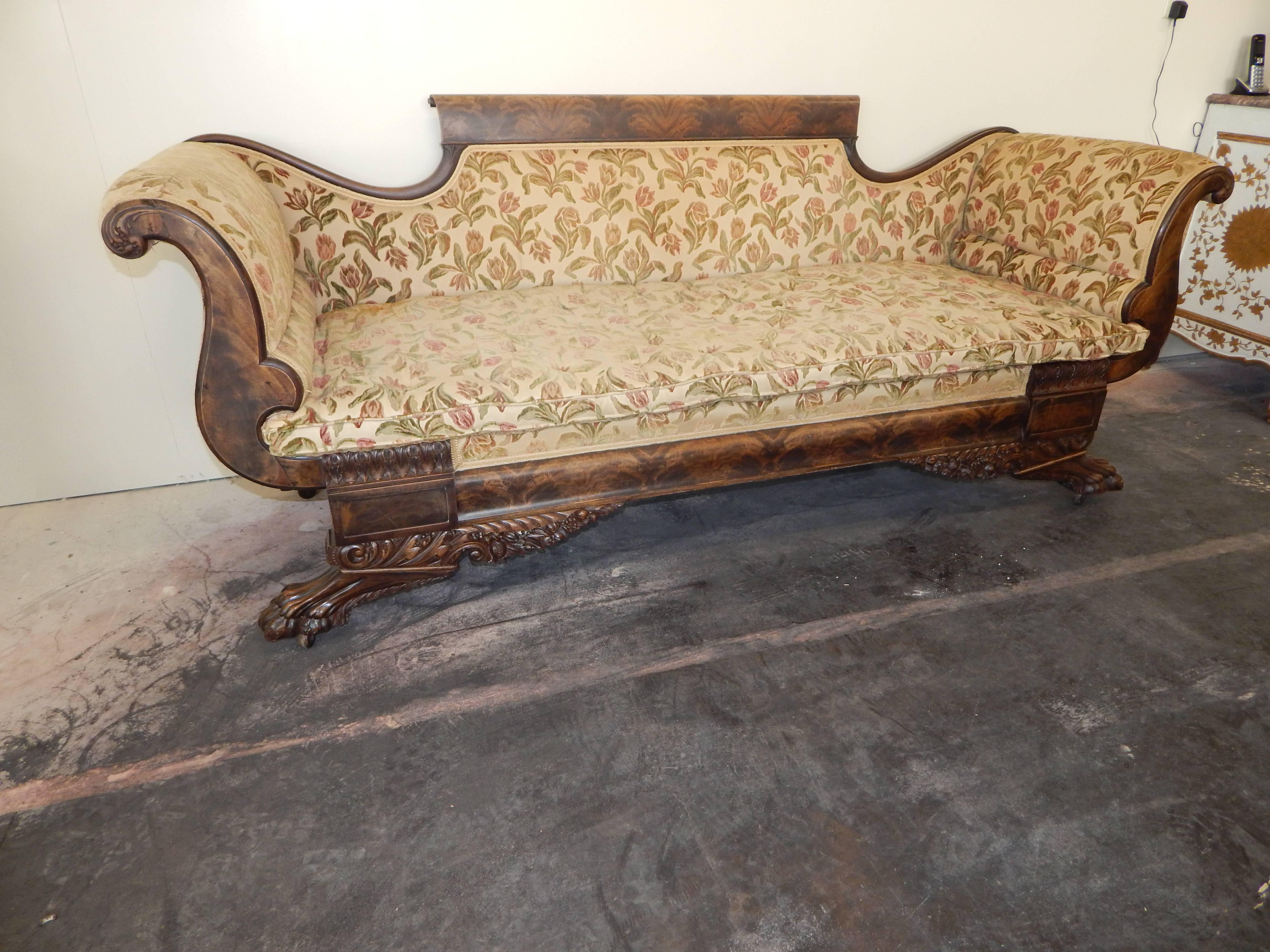 A fine classic American Empire settee with excellent quality carving with cornucopia and paw feet, featuring crotch mahogany veneers.
This is a large and dense mahogany piece, and weighs a ton!

Needs re-upholstering.