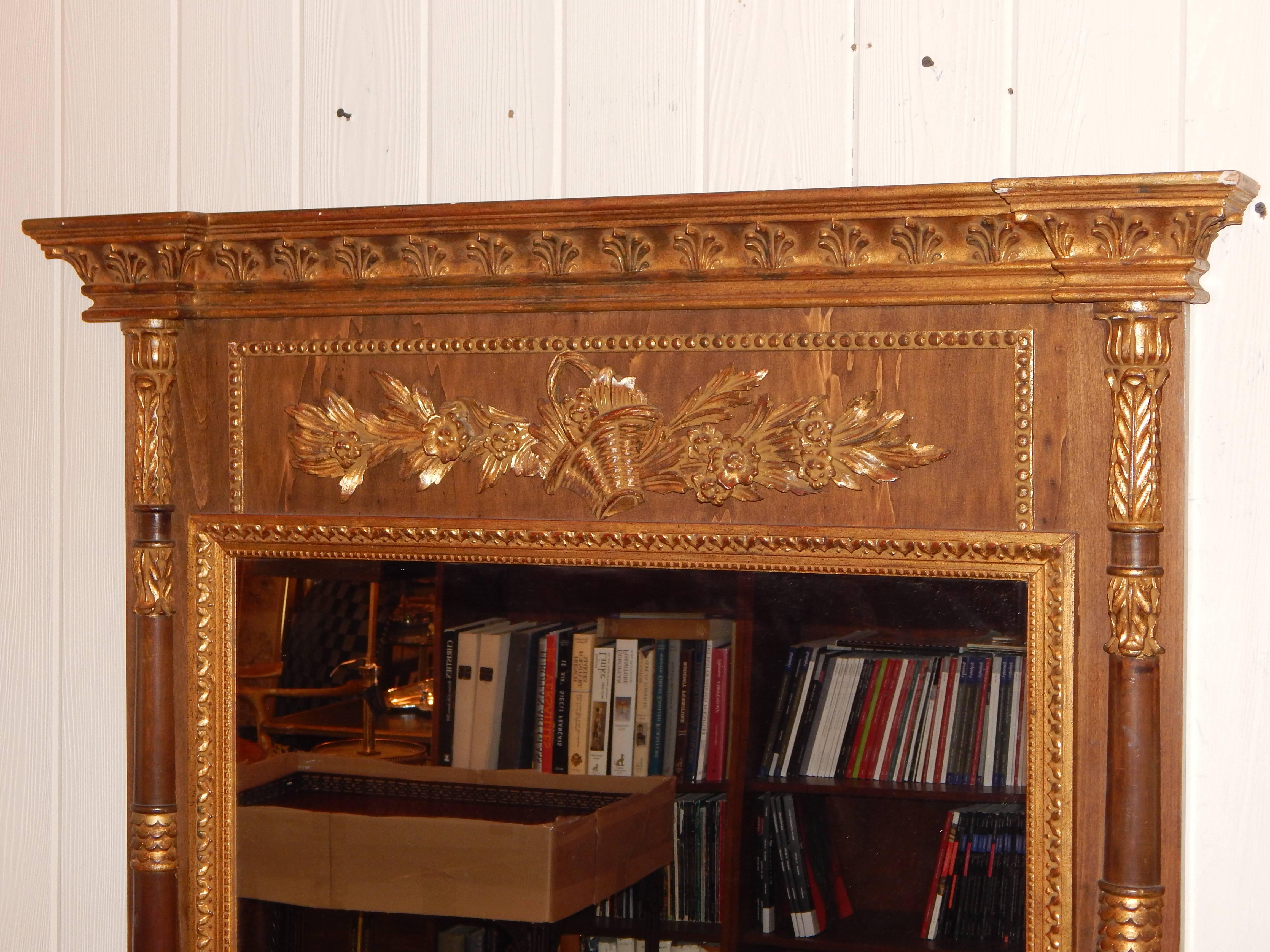 A handsome neoclassic style parcel gilt mirror with columns, and
carved flower basket.