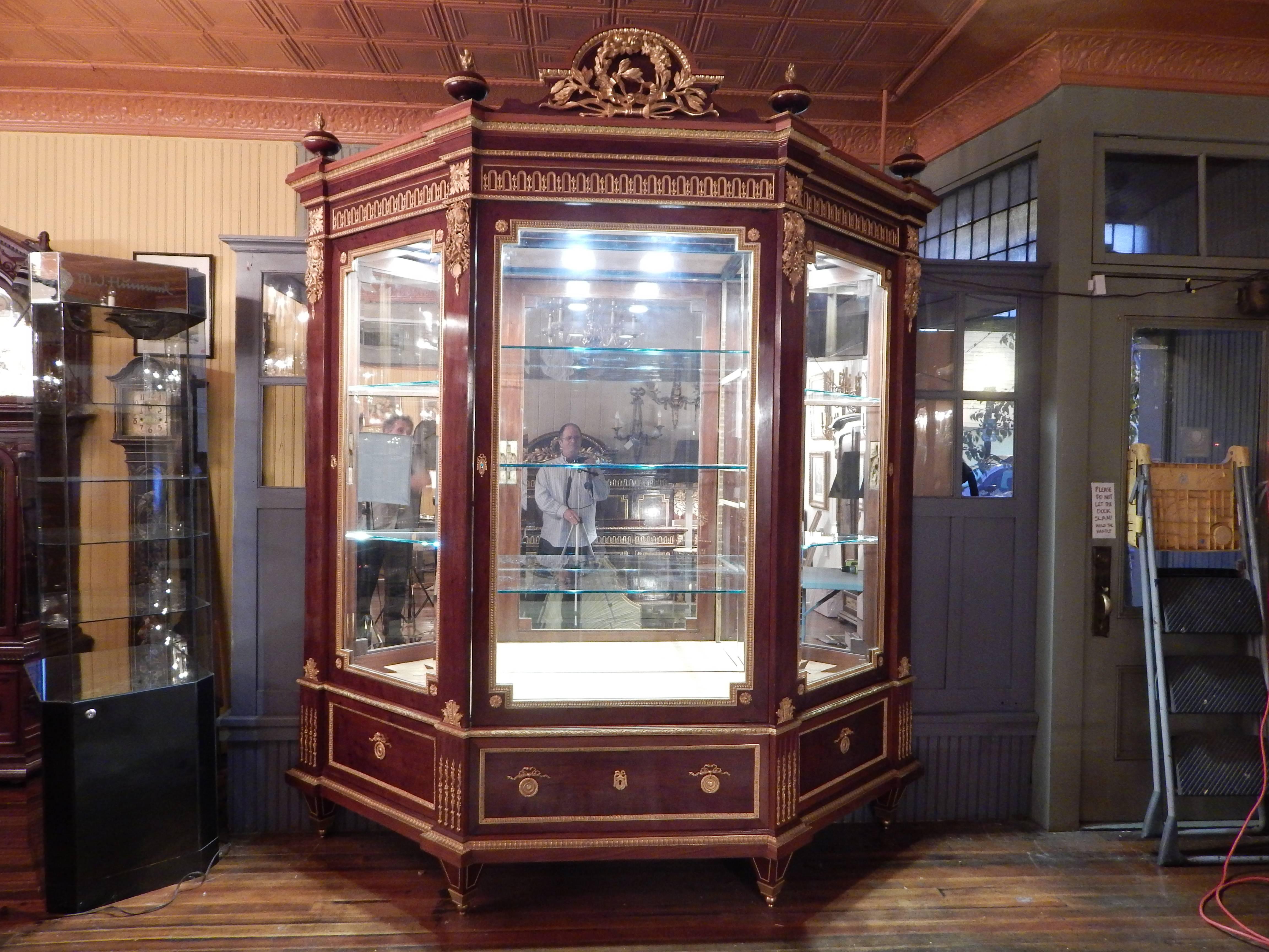 A huge and important 9' tall Louis XVI style ormolu-mounted mahogany three-door vitrine, or curio cabinet, by Guillaume Grohe. Dripping with the finest quality doré bronze mounts, including a huge wreath at the top, flame tip finials, and musical