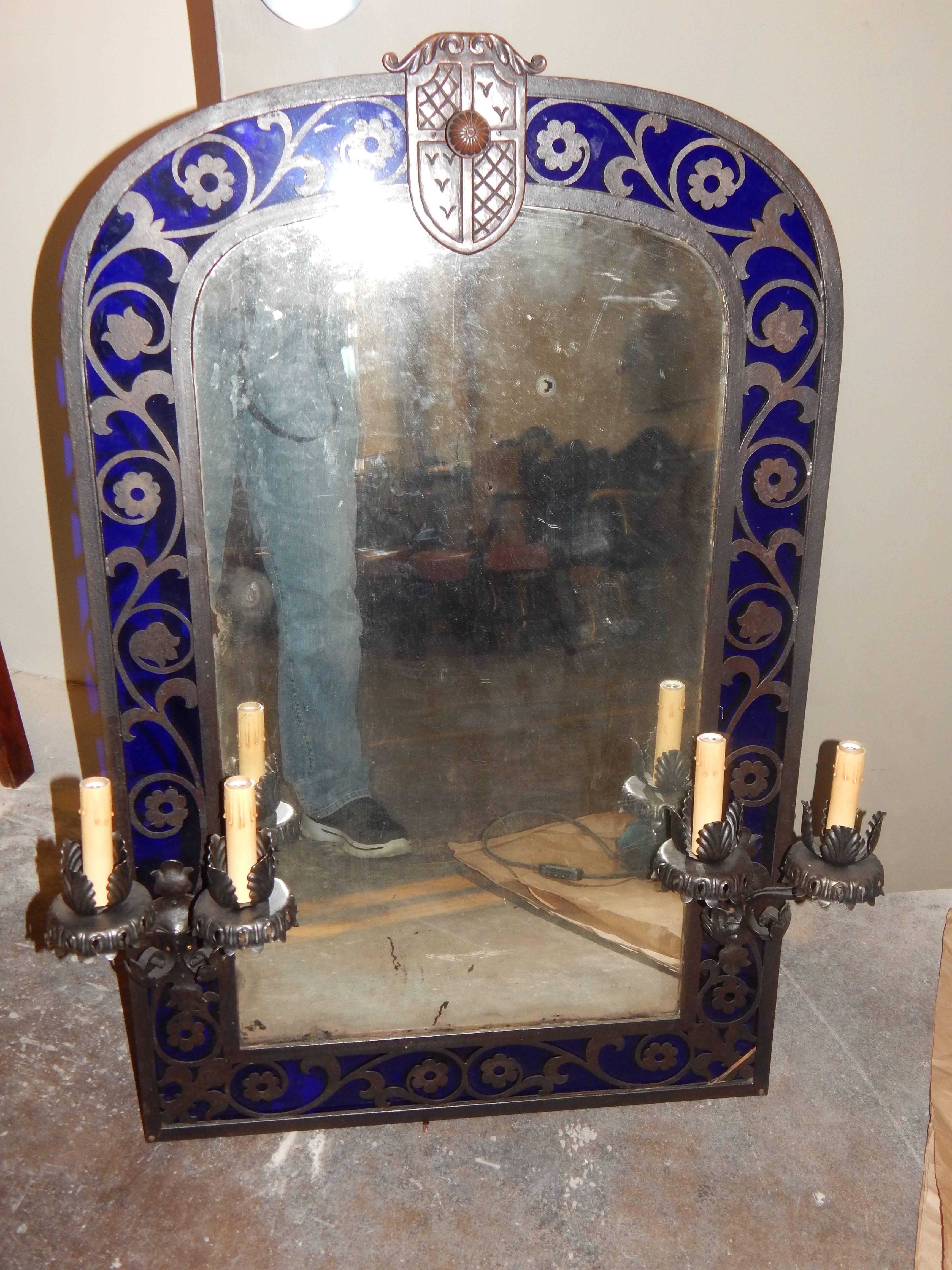 A striking and unusual pair of Renaissance style patinated metal mirrors, with sconces, surrounded by vibrant cobalt blue glass.