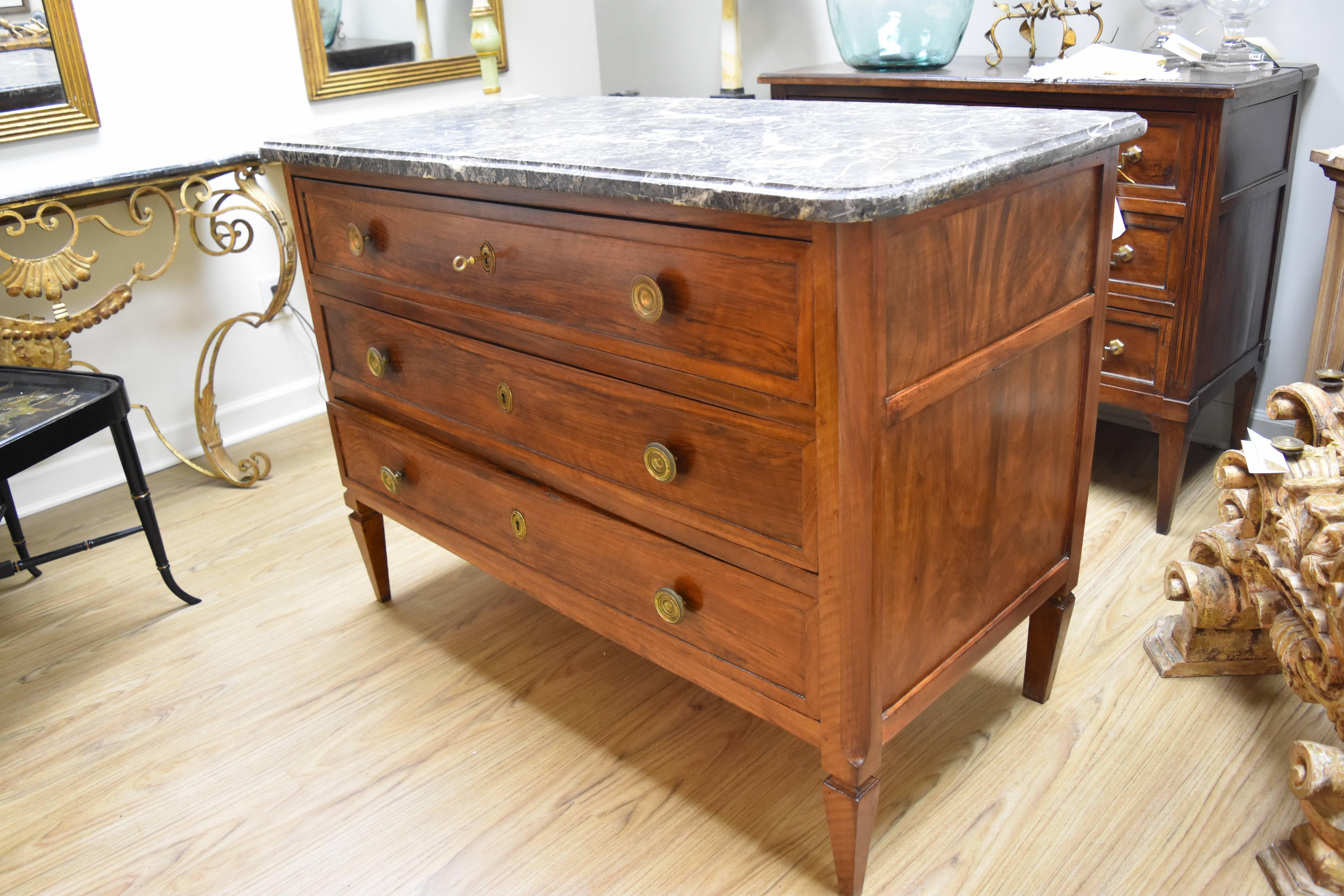 This 19th Century Walnut Commode features the original brass hardware and key as well as a beveled marble top.  The drawers are all functional and the legs are simply tapered.