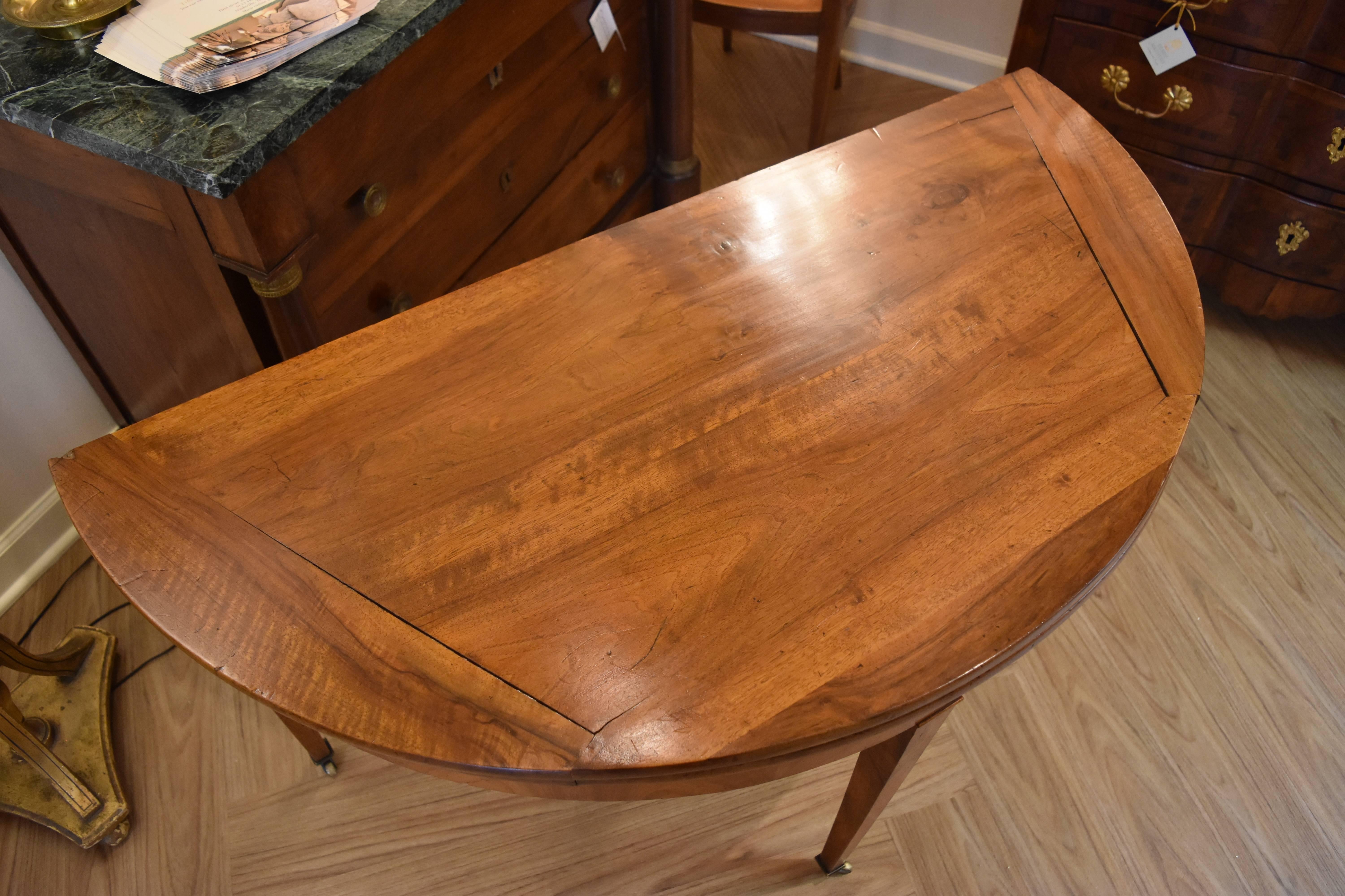This 19th Century French Walnut Demilune is in excellent condition and features an interesting geometric wood design on its' top and lovely tapered legs on casters.  It can be used as a round dining table or closed as a side table.

24 inches deep