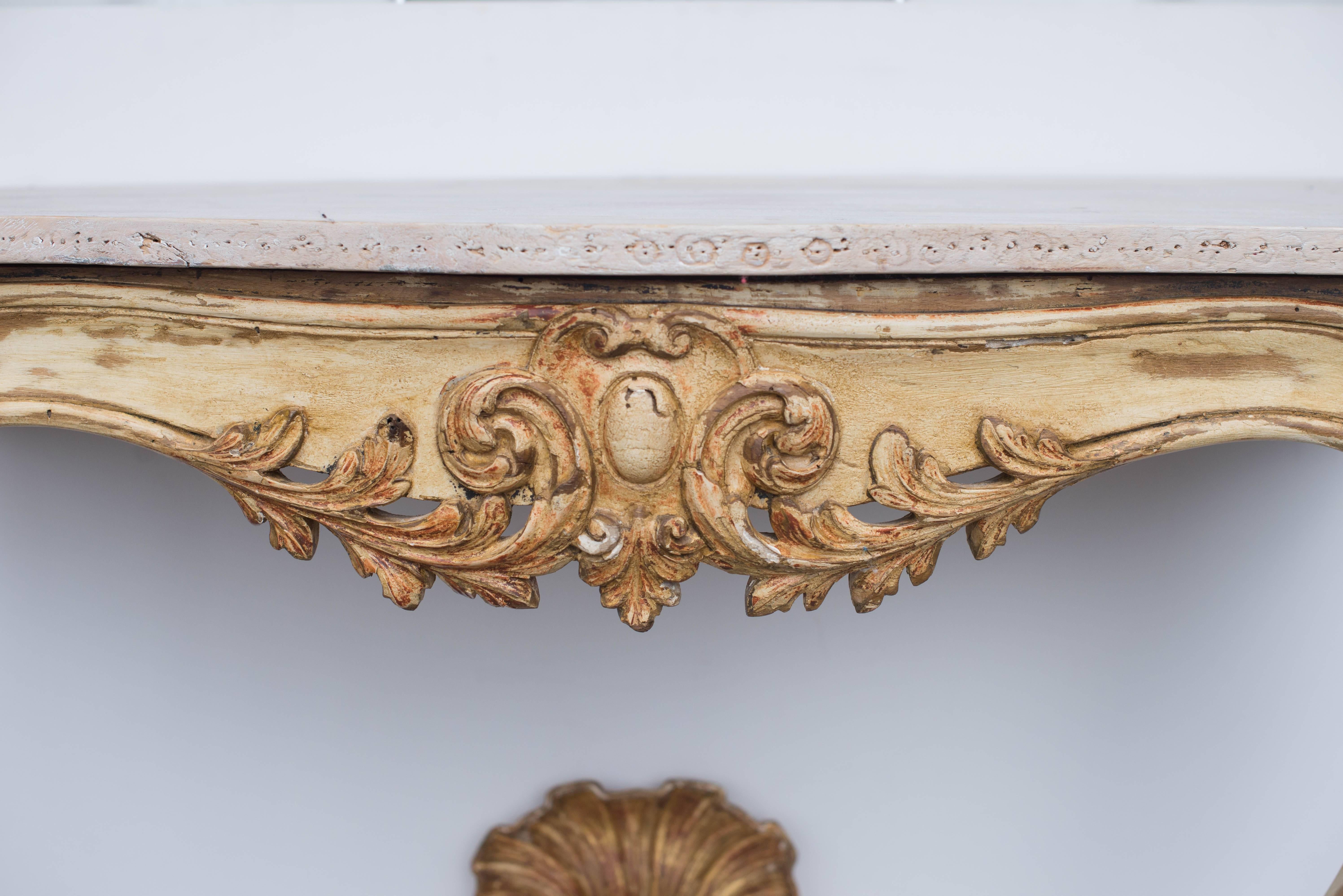 This 19th century French wall console has a giltwood and rich creamy painted finish. It features lovely wood carvings and cabriole legs. The top has a cream colored painted finish but could be painted any color. This item was purchased in Aix en