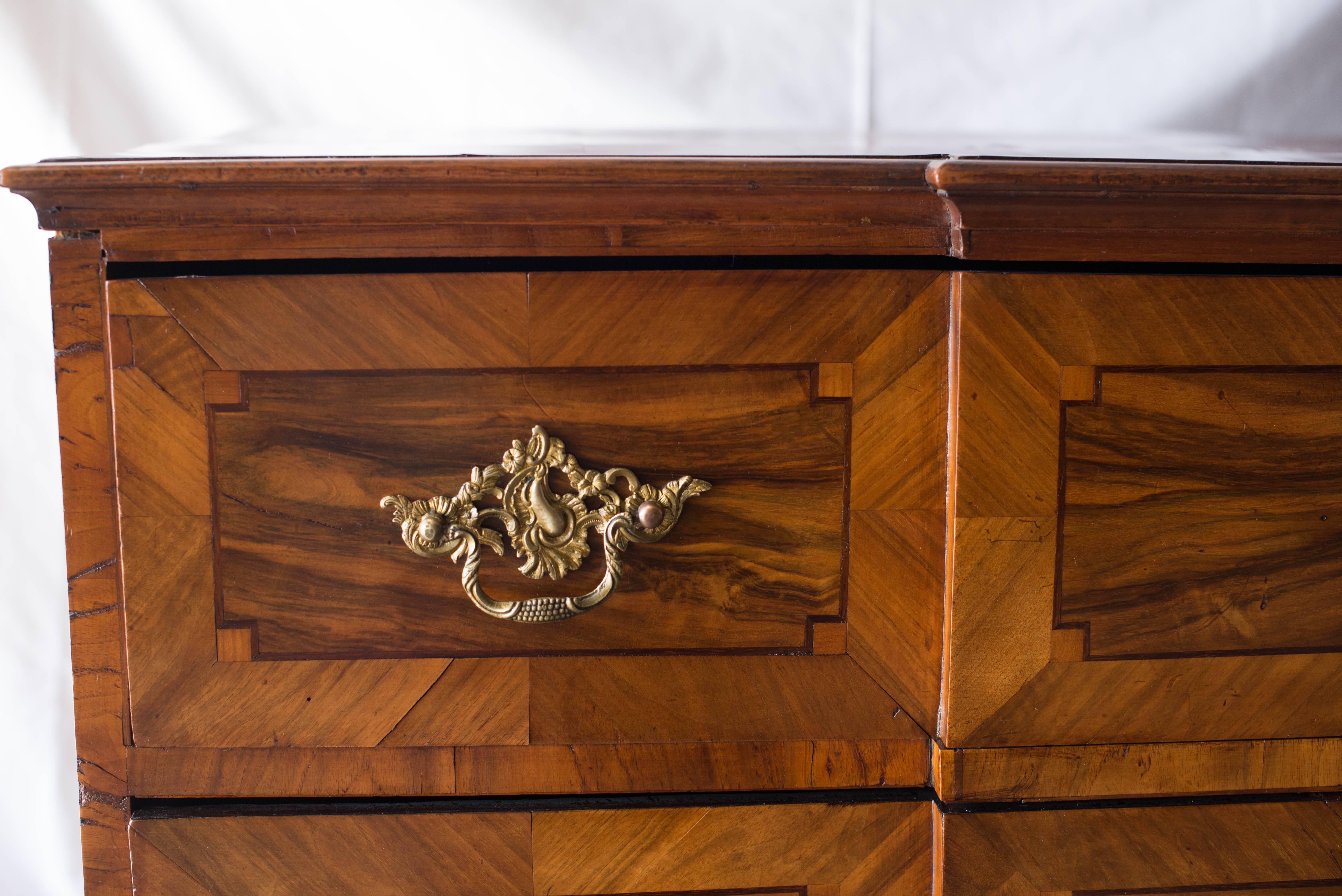 This German Baroque Commode, circa 1740, features walnut veneer with intricate intarsia on the front, sides and top. There are several places on the top where the veneer is lifting slightly but it in no way diminishes the overall beauty of this