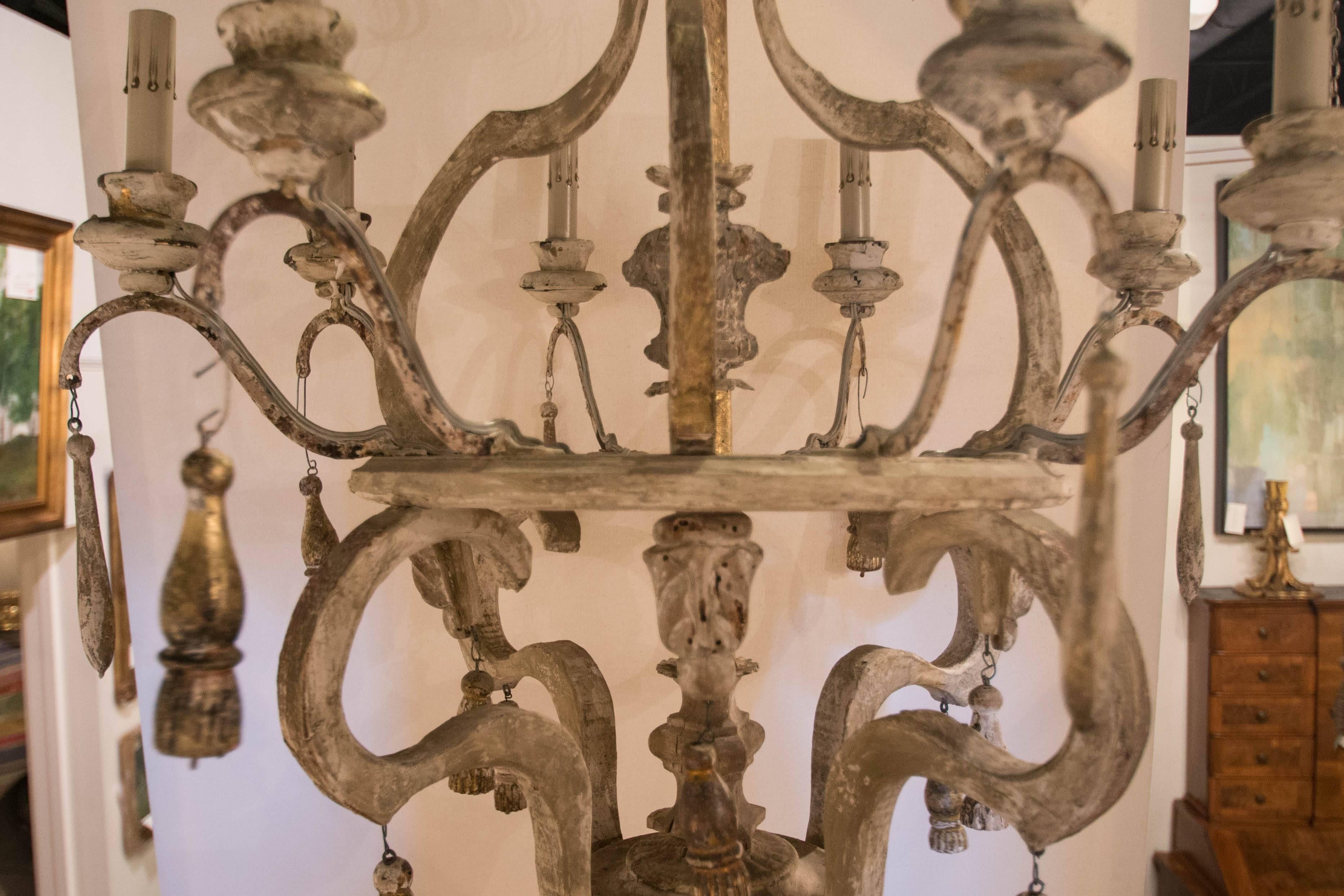 This very unique Italian chandelier is made mostly from 19th century parts and has been wired for American use. This chandelier features eight iron arms with a lovely creamy painted finish. The tassels are mostly gold leaf. The patina is wonderful
