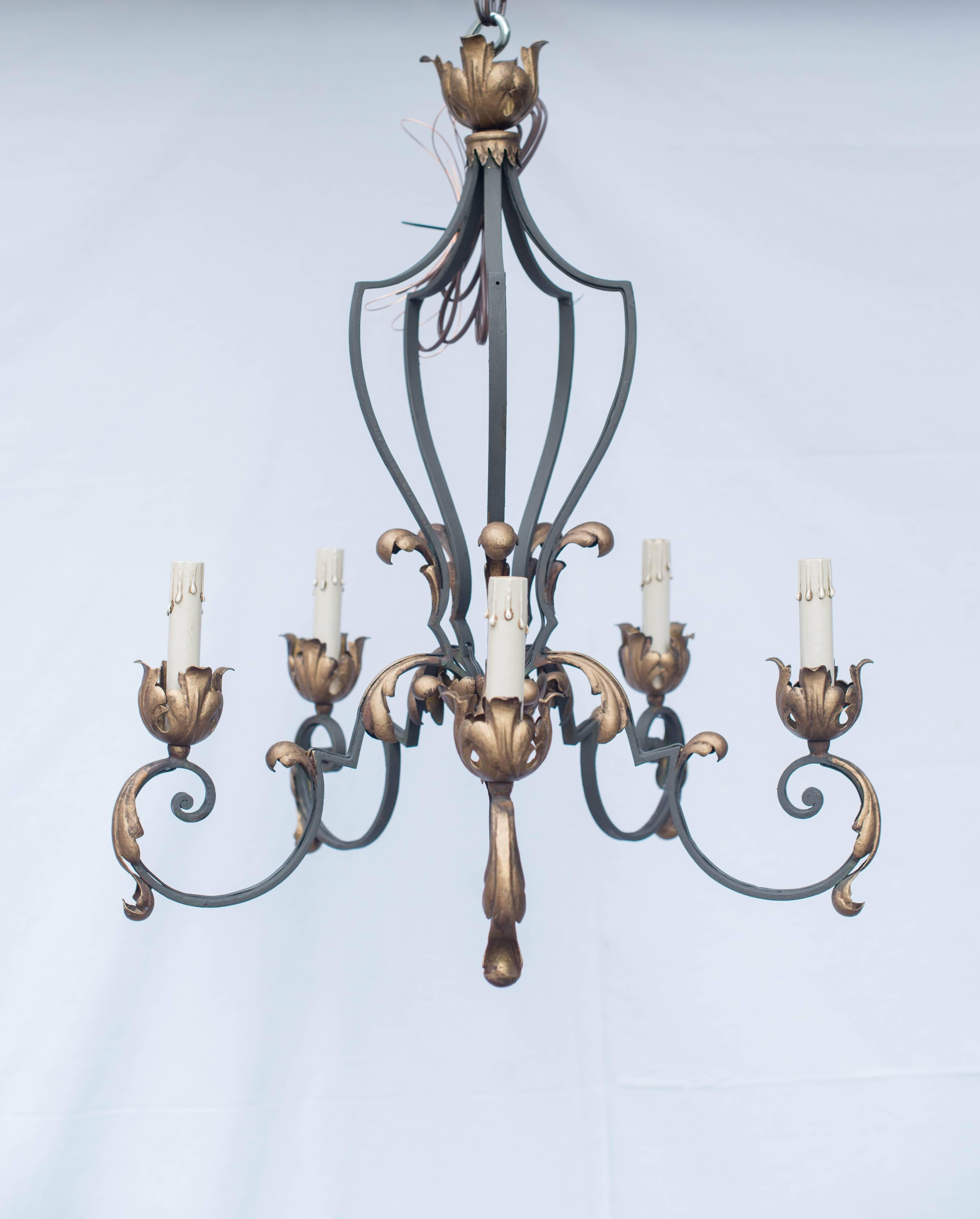 This beautiful early 20th century painted French iron chandelier features six scrolling iron arms adorned with acanthus leaves. The finish is bronze like with touches of gilt on the leaves. This chandelier has been newly rewired for American use.