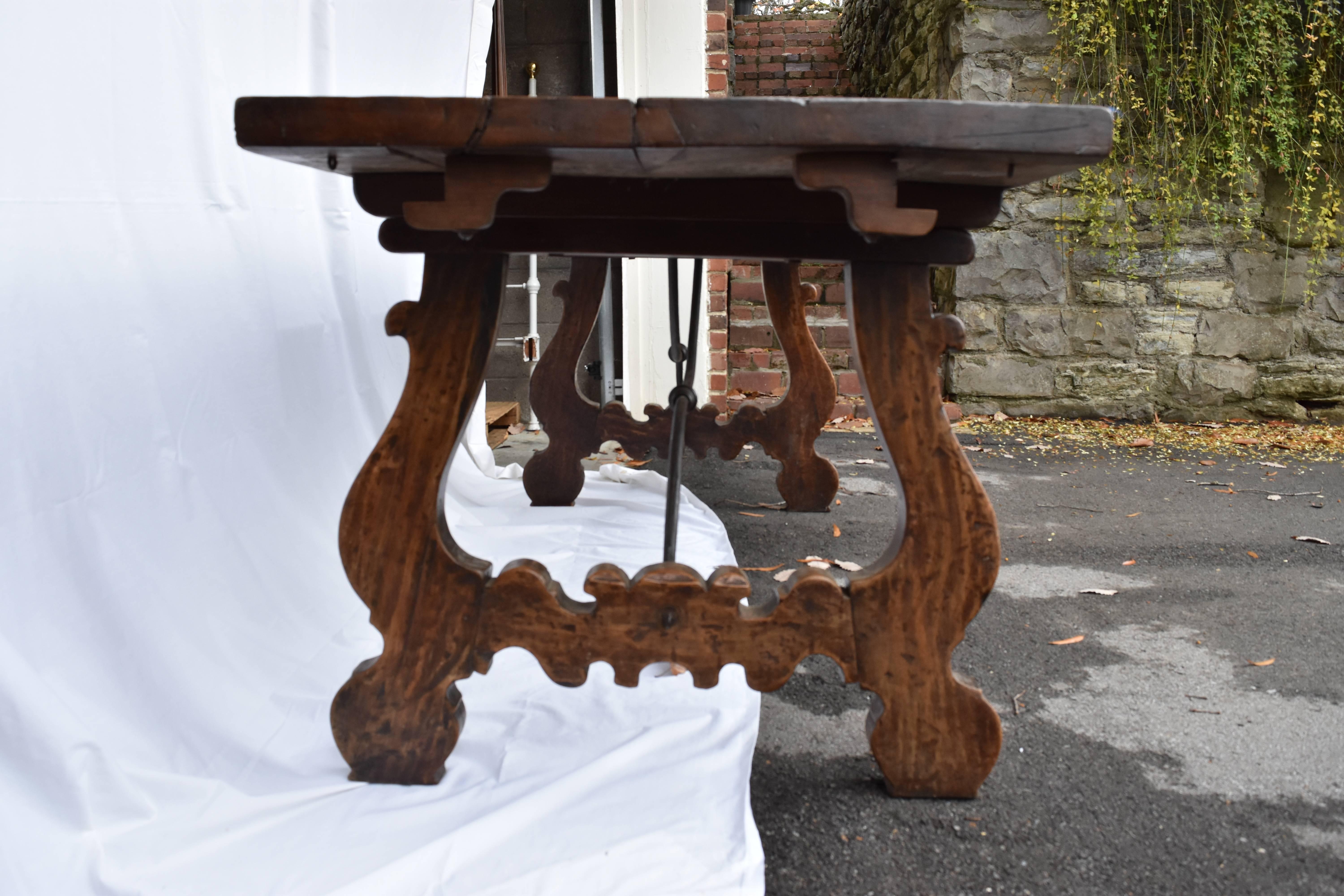 This 19th century Italian refectory table has the traditional lyre legs and iron cross. The top is walnut and has not been touched up.
