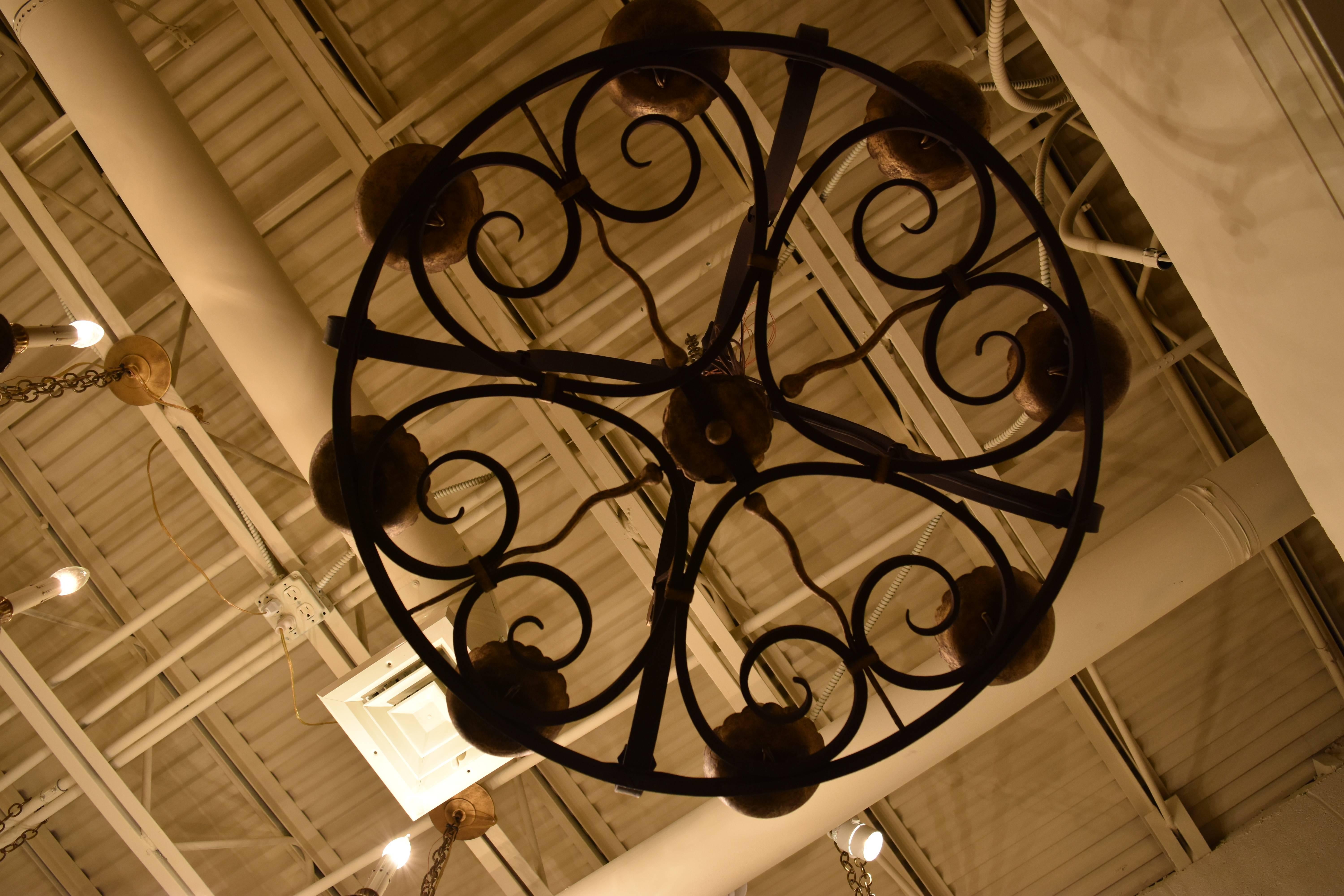 This early 20th century iron chandelier has eight lights and has been newly rewired for American use. The finish is a bronze like color with gilt accents.