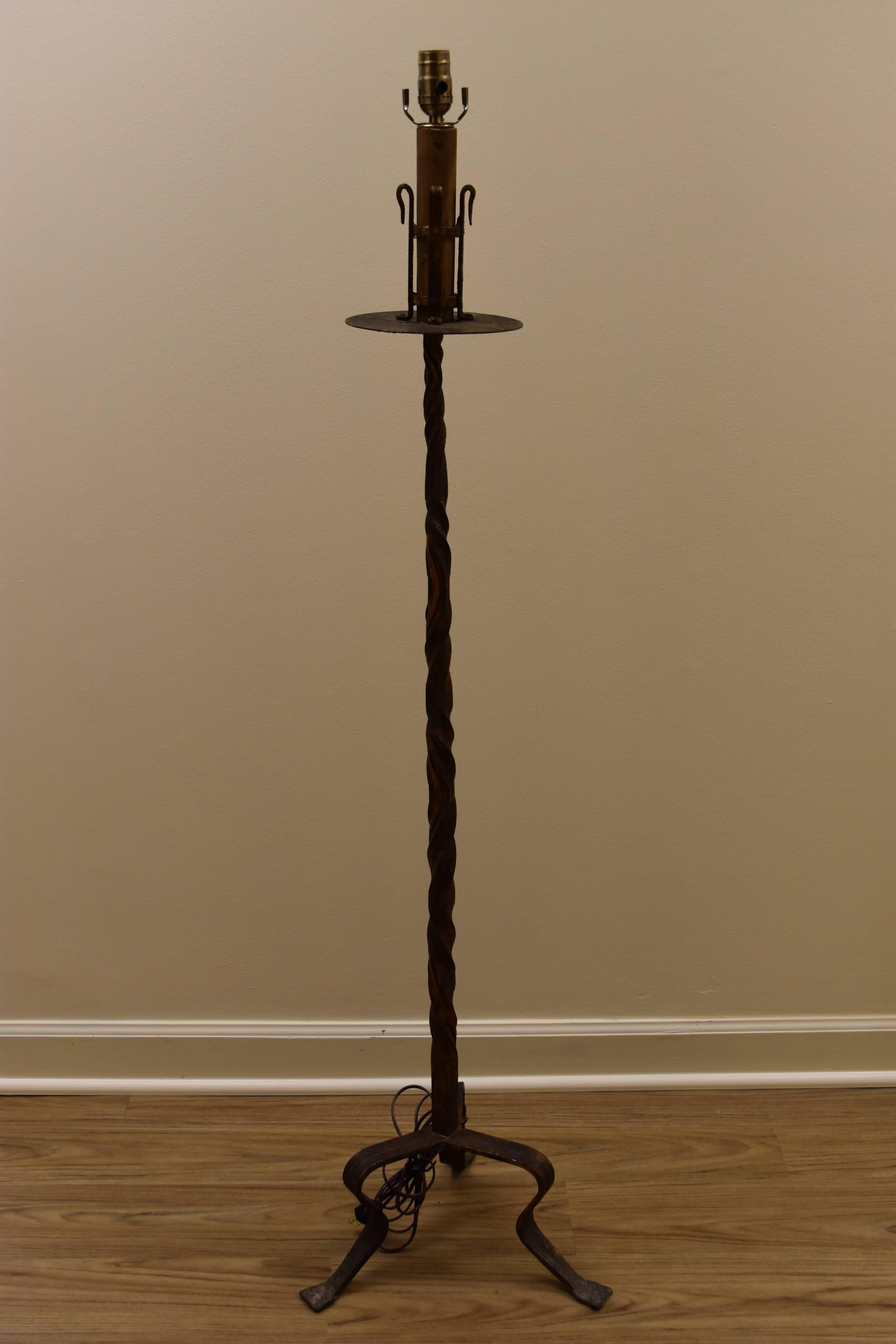 This iron floor lamp is from Barcelona and comes with the new linen drum shade and finial shown. This lamp has been newly rewired for American use and features a transitional design on the column with three legs at the base. The finish is a rich