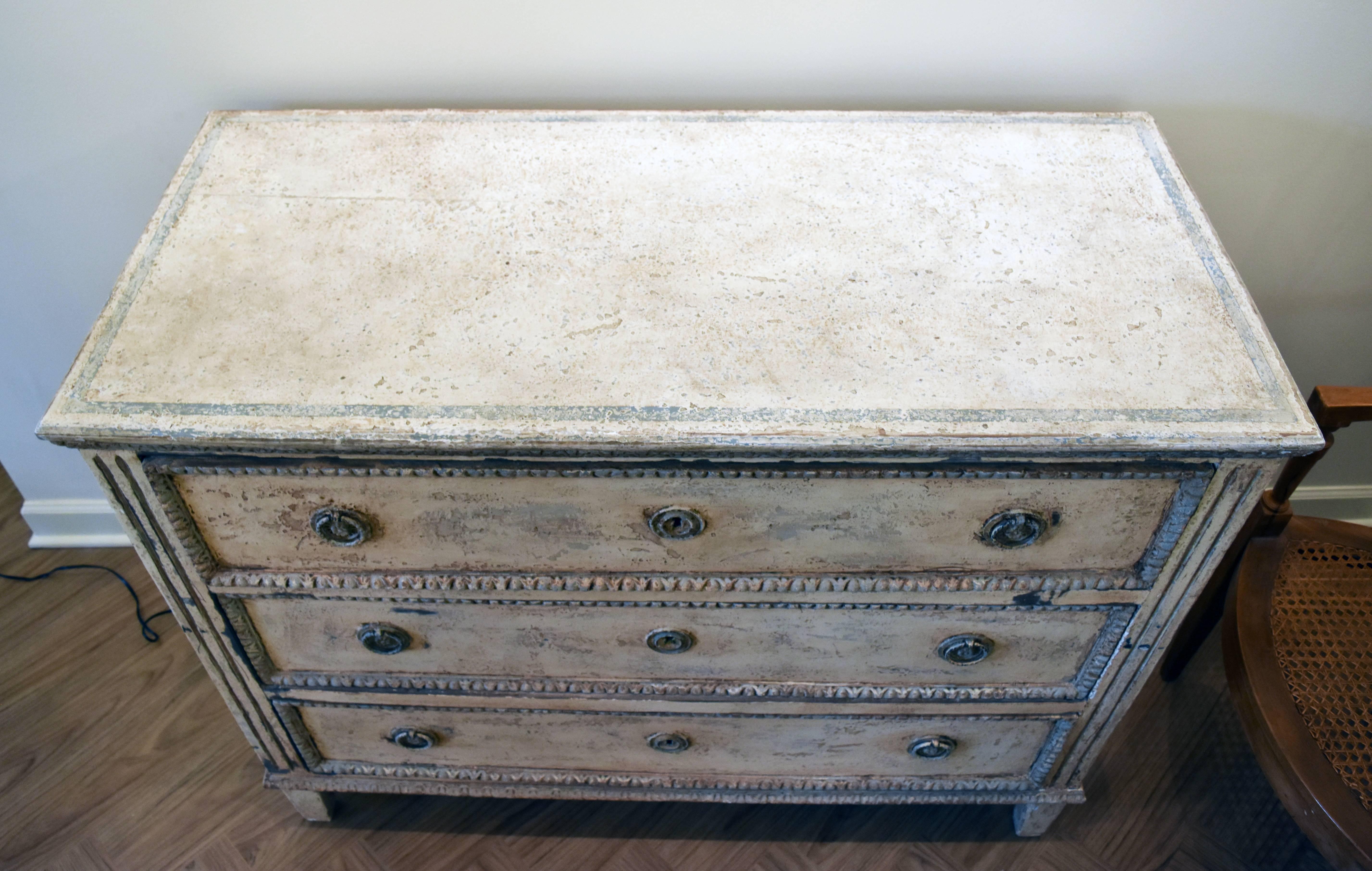 This 19th century Louis XVI style painted commode is from the South of France. It has three working drawers and a lovely creamy finish with pale blue accents and warm undertones.