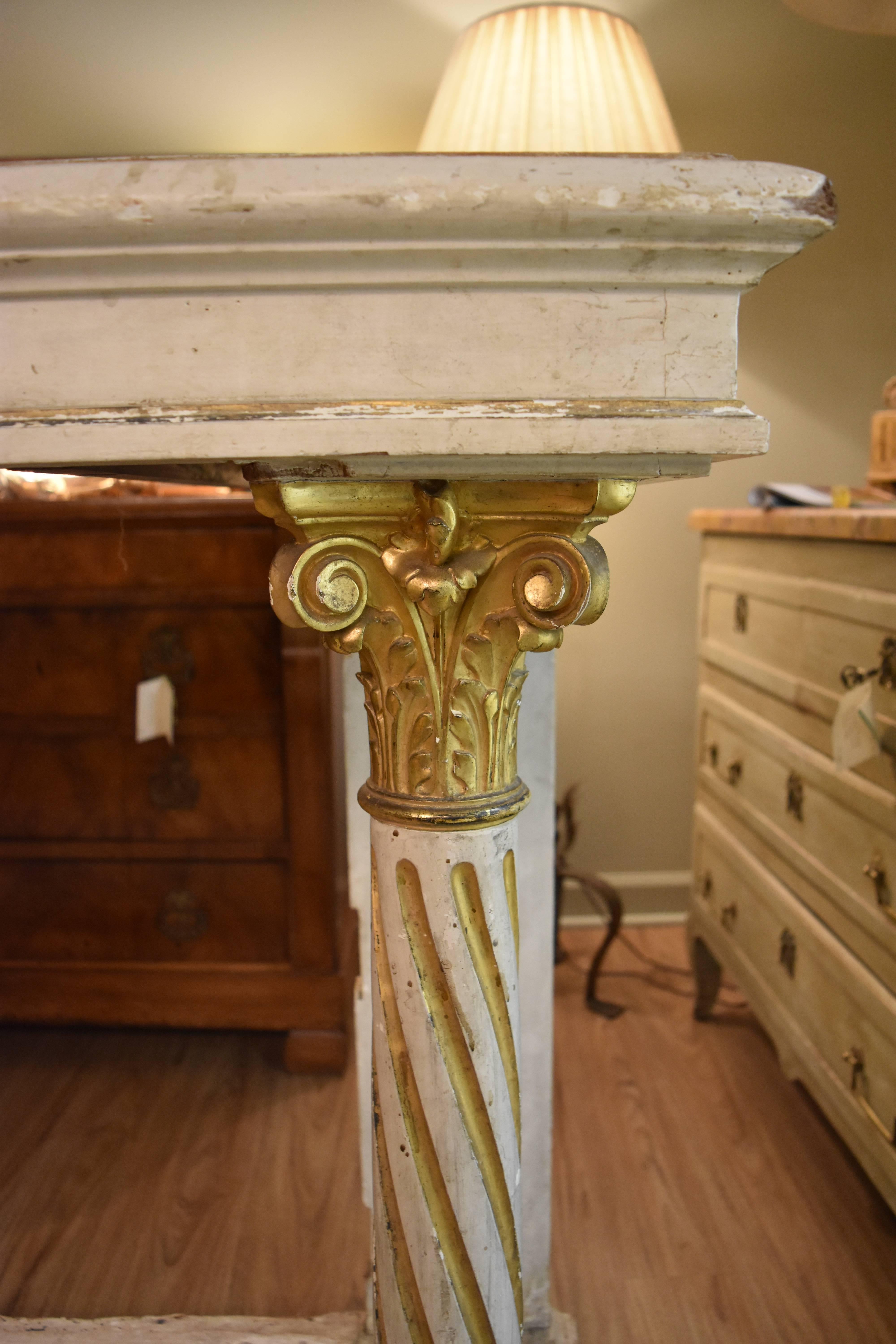This 19th century, Italian painted console is in the neoclassical style. The Corinthian column legs are mounted on a raised plinth base. The finish is a rustic creamy painted finish with gilt accents on the columns.