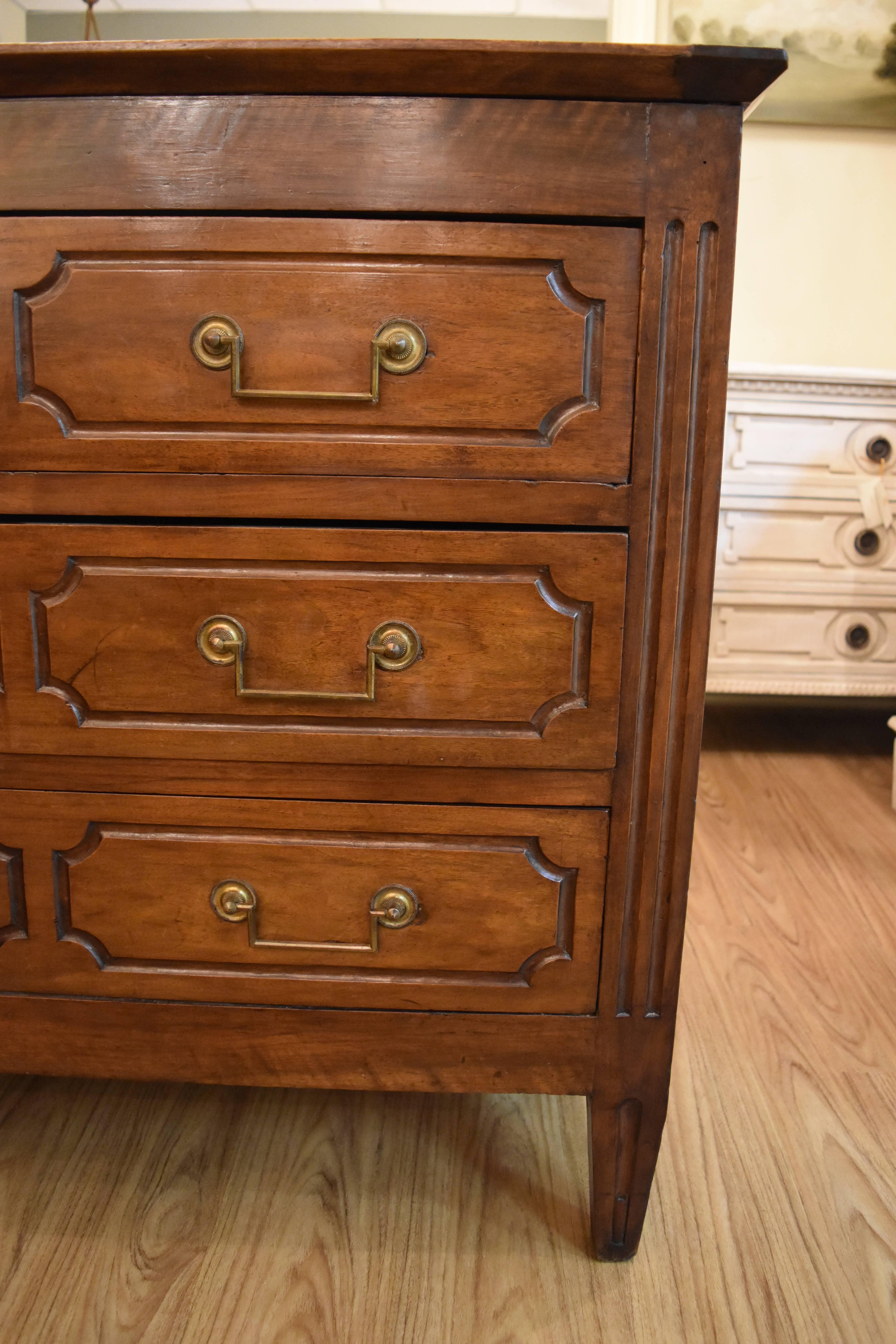 This walnut three drawer commode features tapered legs and beautiful brass hardware. The drawer design is geometric and would mix well with today's more transitional decor.
