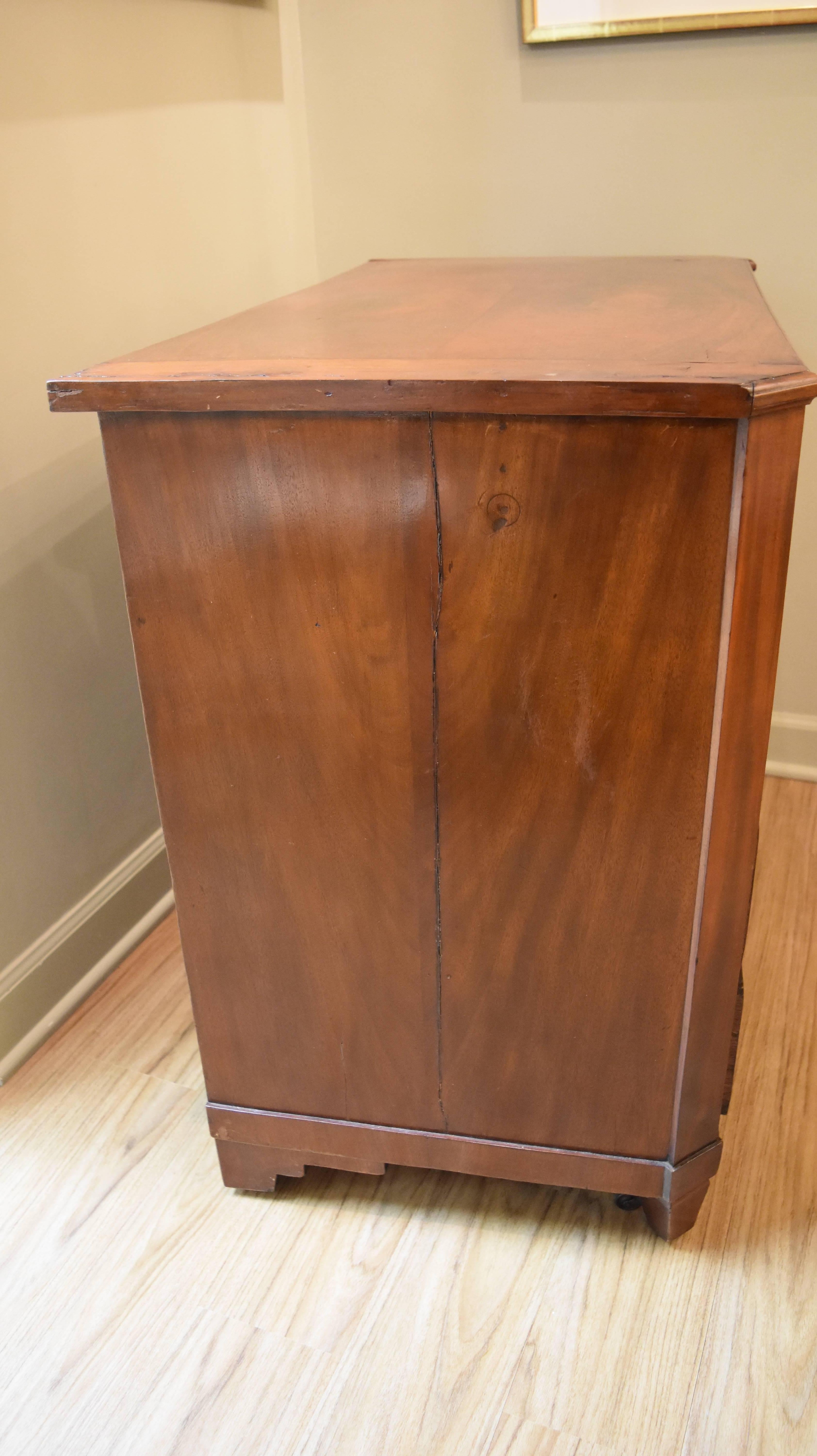 This early 19th century mahogany chest is from Belgium and has four working drawers. The oval pulls and key escutcheons are brass and the front legs have hidden casters. The small size makes it perfect for a bedside table or hallway chest.