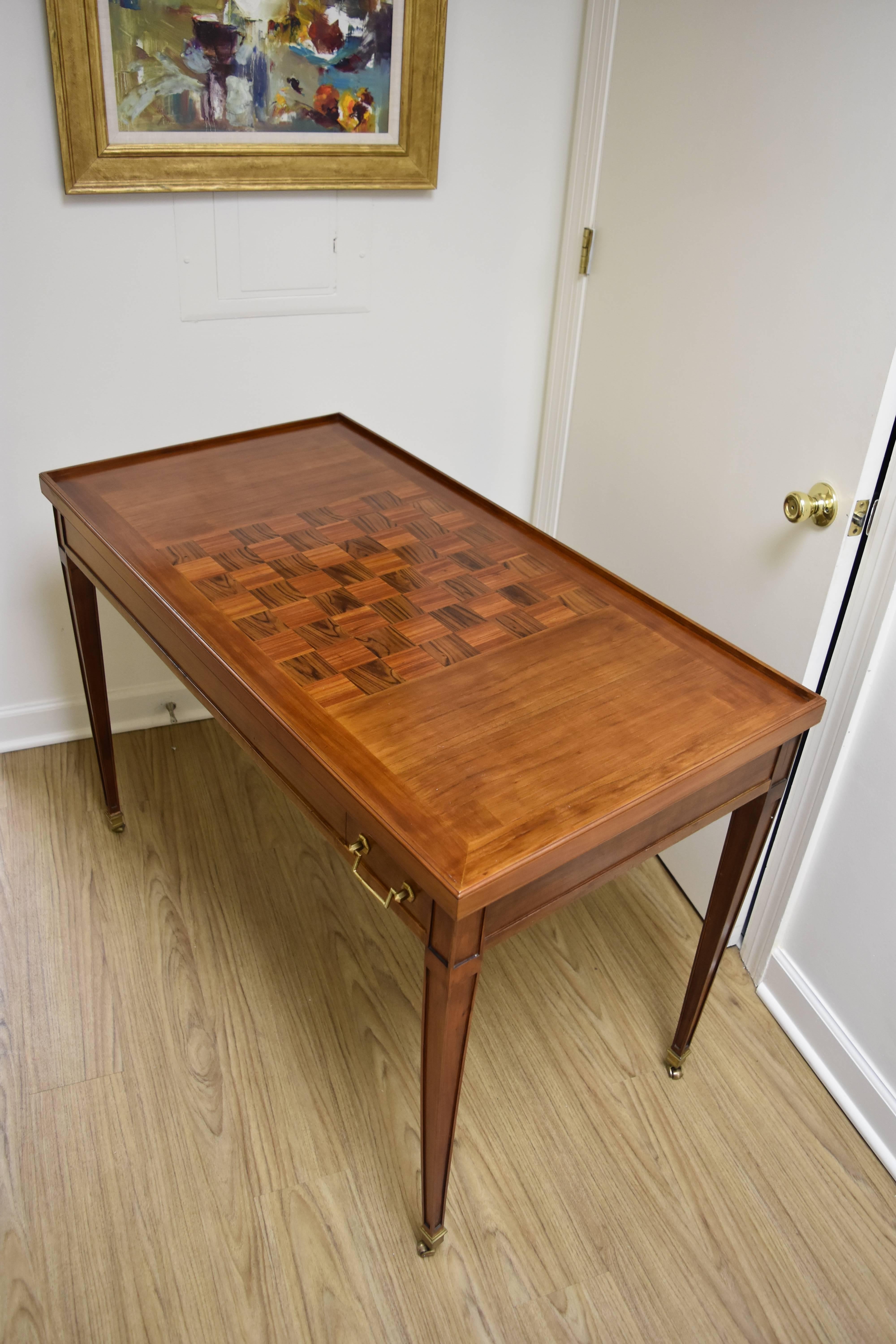 This unique Louis XVI Style Walnut Game Table features a reversible top.  The top has an inlaid checkerboard design on one side and felt on the reverse.  Underneath the removable top is a backgammon board.  The felt is in good condition with several