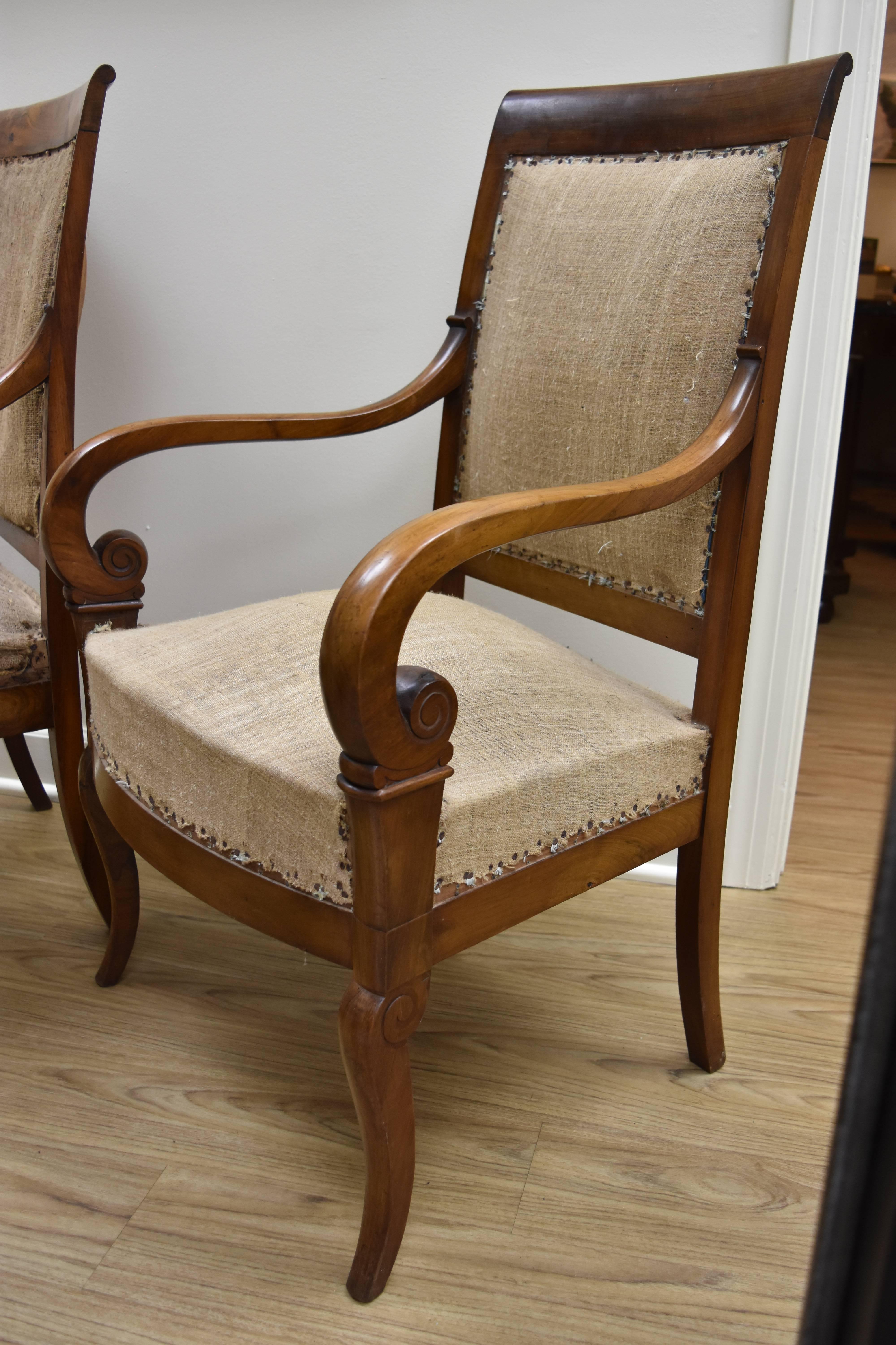 This pair of Empire style walnut armchairs has a lovely warm walnut finish and features scrolling arms. The chairs need to be reupholstered but are shown with the original old nails and burlap fabric.