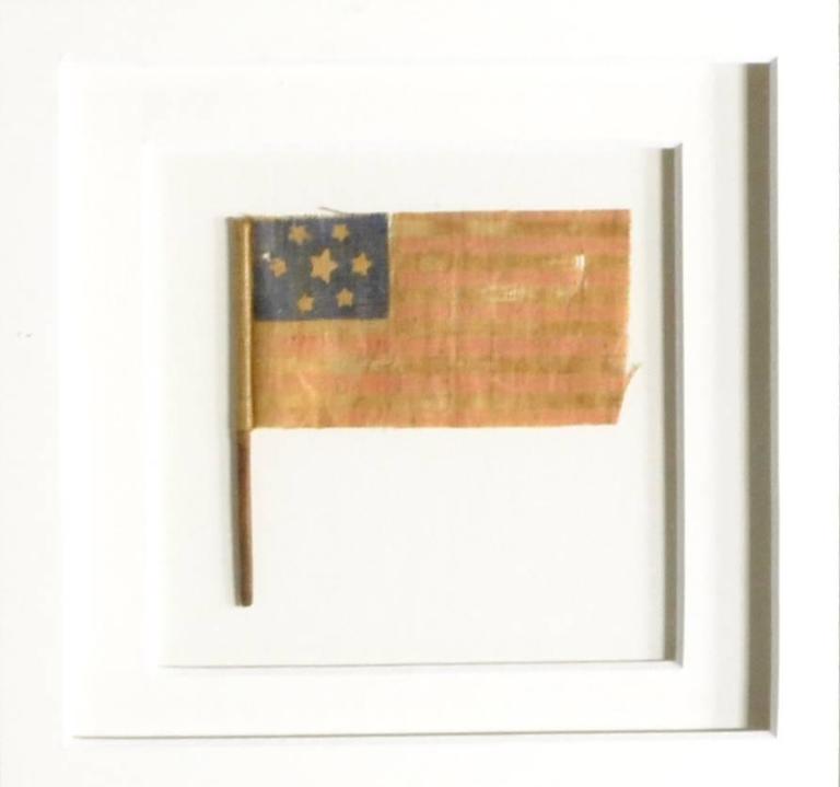 Early Civil War parade flag with seven stars. The seven signifies the first seven states to seceded from the Union. They also made these with eight stars and nine stars as more states seceded. Made of starched gauze material and glued to a small