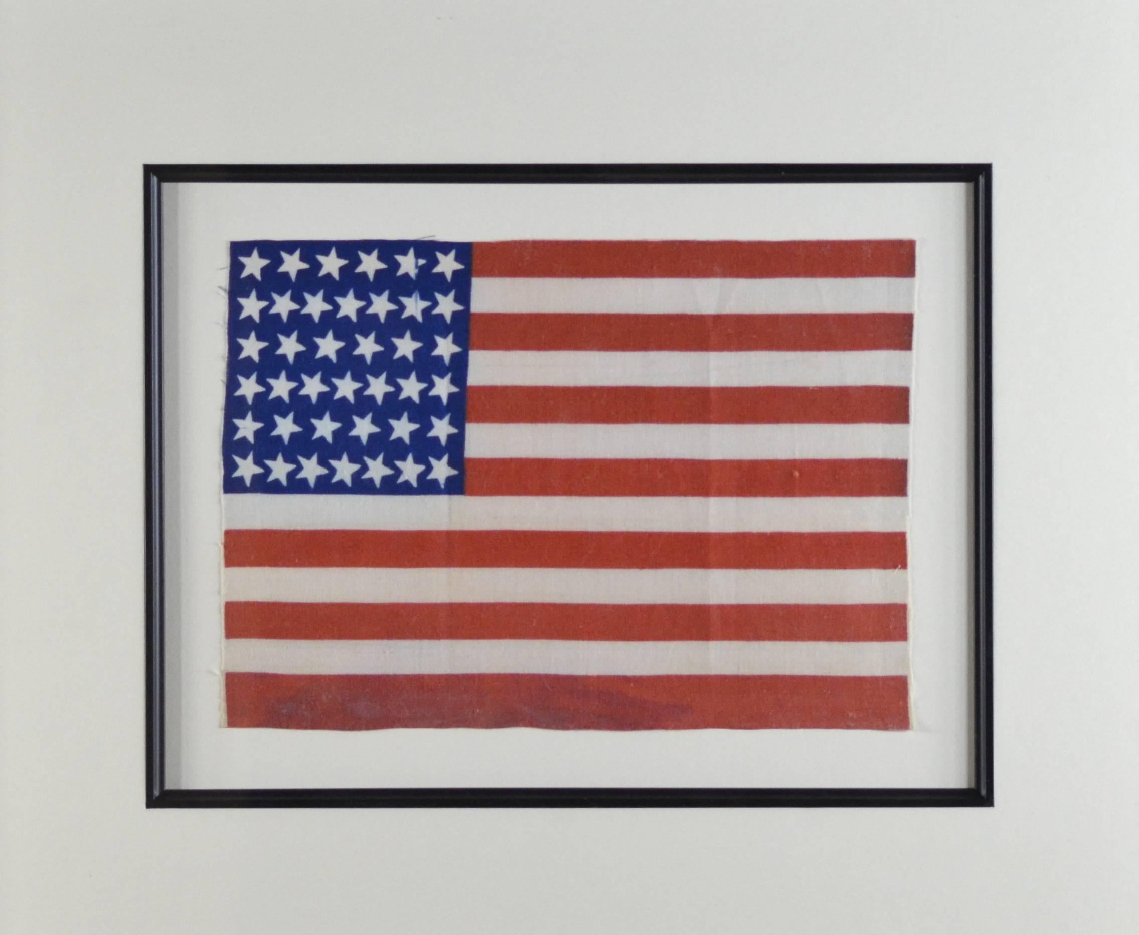 Authentic, antique 39 star American flag. Professionally framed with museum materials and UV acrylic. Has a cool star arrangement as the stars look like they are spinning. Unusual flag as the bottom red stripe is fatter than the others. Made of