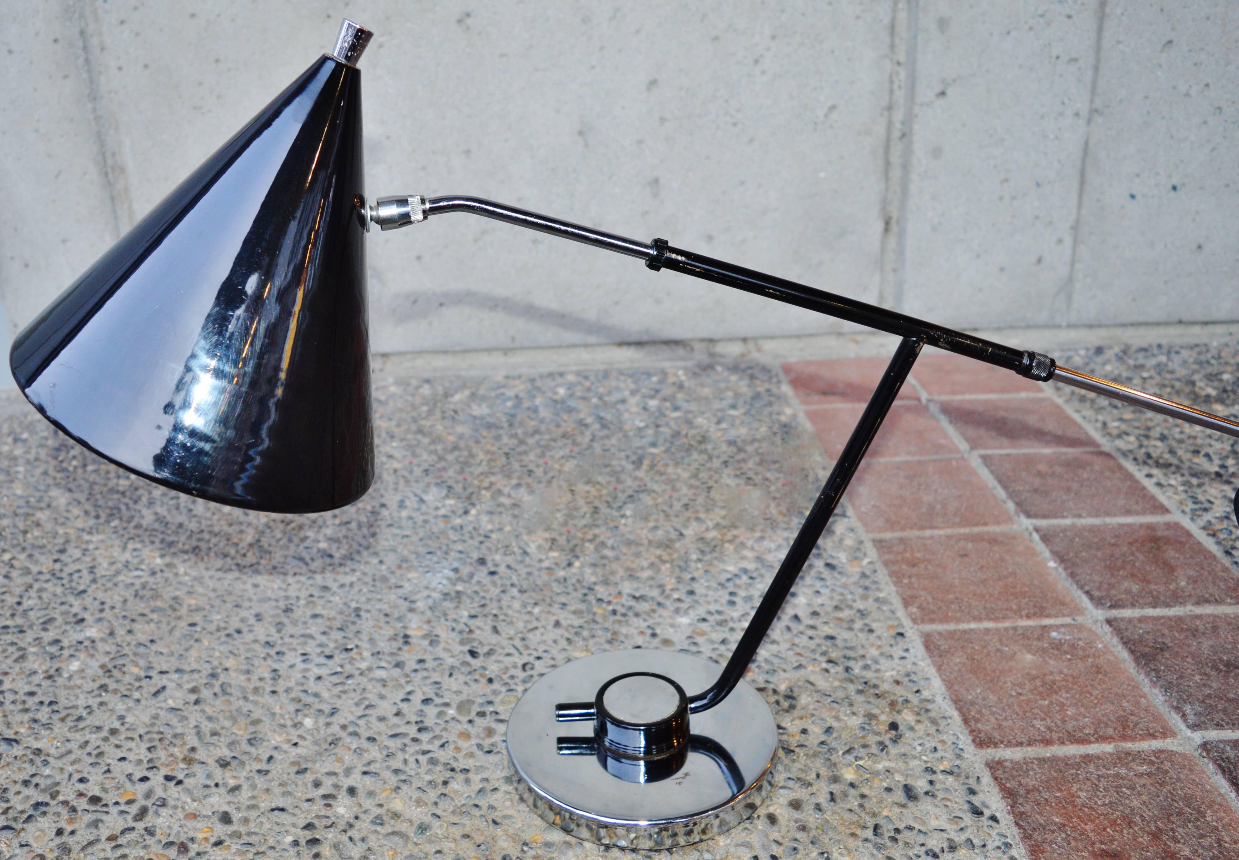 This is a totally hot Mid-Century Modern adjustable desk lamp! Featuring high gloss black painted metal conical head and stem with chrome accents and base. The base allows for one to swivel the lamp as desired, the articulated hardware allows one to