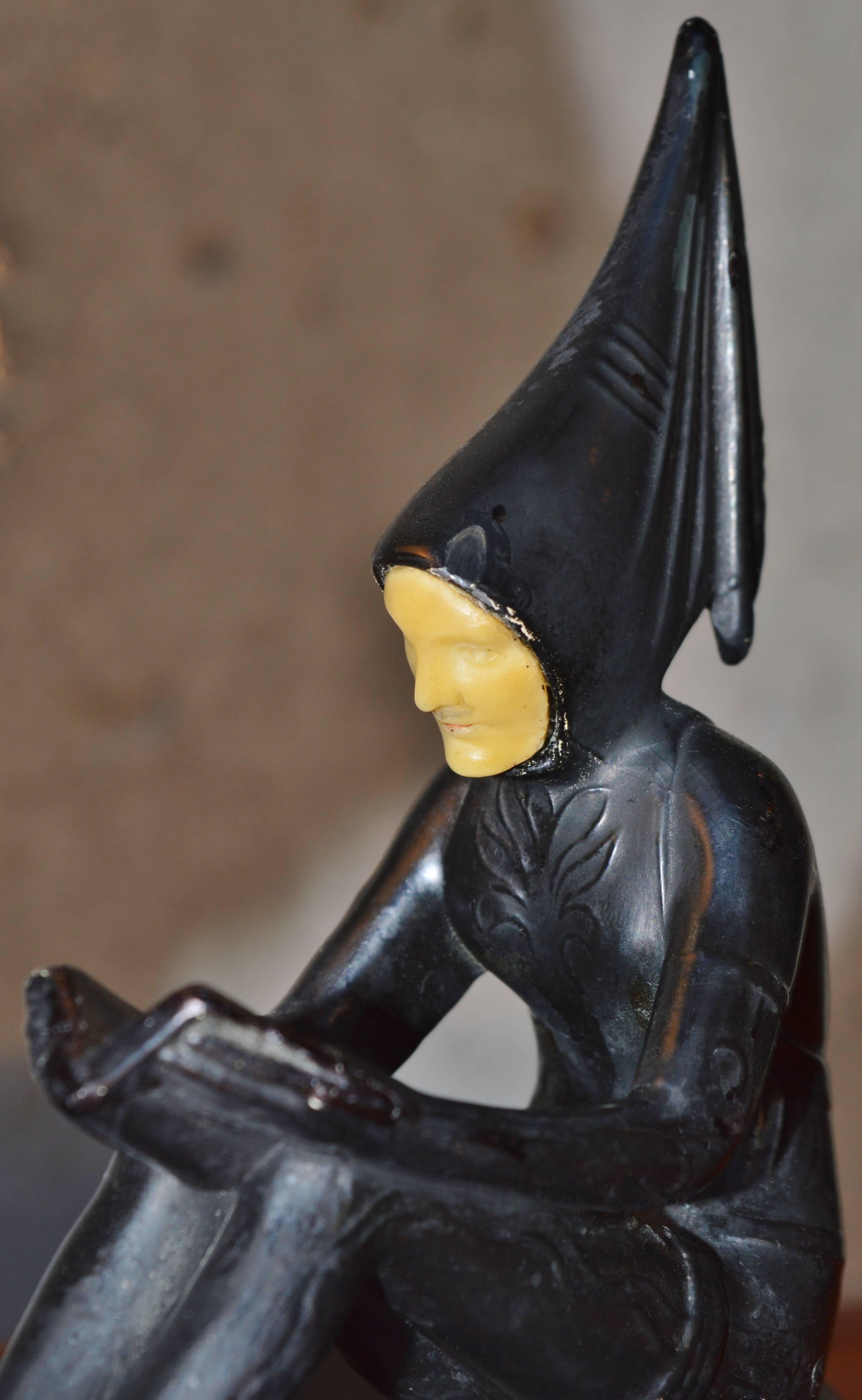 This Art Deco small lamp is truly striking! Featuring a metal Harlequin figure with a pointed hood, reading a book, on a metal pedestal with edge decoration. Also referred to as 
