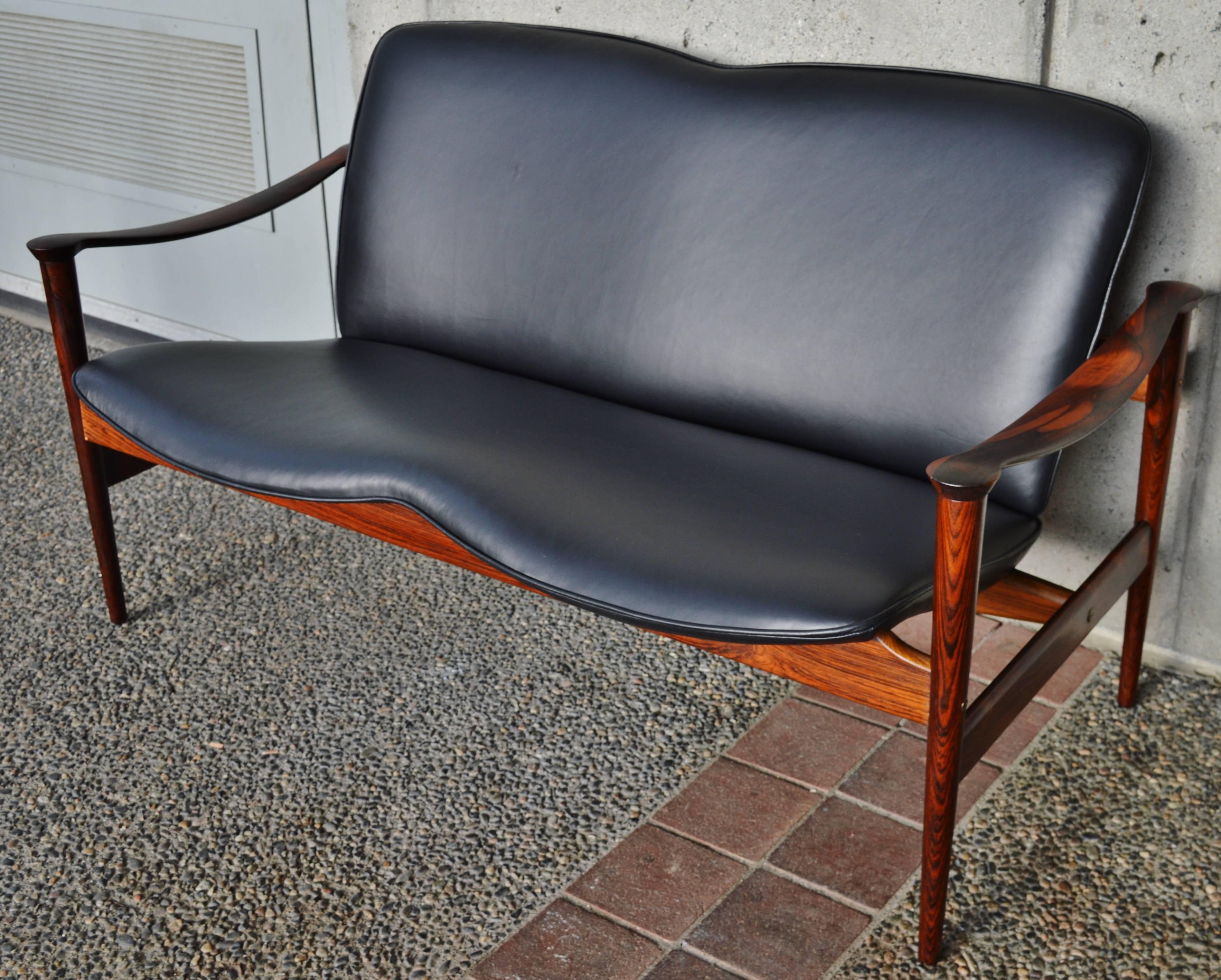 This impeccable Danish Modern rare rosewood loveseat / sofa was designed by Fredrik Kayser for Vatne Lenestolfabrikk, Norway, in the 1950s. The gorgeous sculptural frame that hugs the contoured seats with ribbon-like curved armrests and amazing