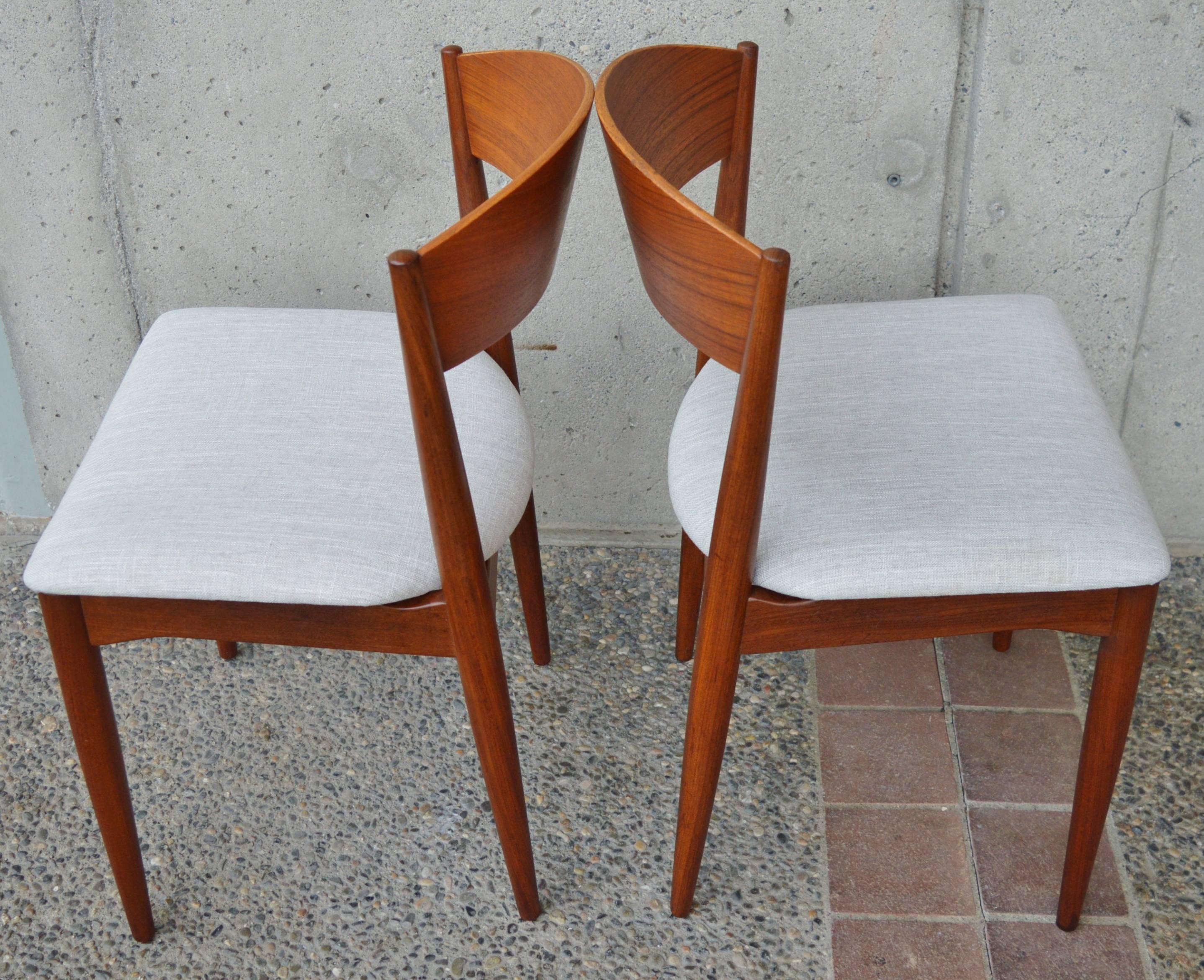 This stunning rare set of eight Danish Modern teak dining chairs have been completely restored and reupholstered, made by Jydsk Mobelindustri Skanderborg (Denmark). Featuring lovely two-tone detailing with the darker teak frames and the bent ply