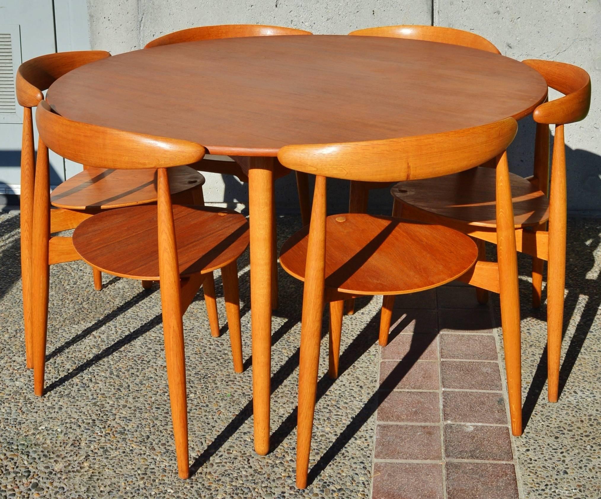 This incredible highly acclaimed early design by Hans Wegner is known as the Heart Dining set that was produced by Fritz Hansen in the 1950s. The tabletop and seats are teak, the table base/legs and chair frames are oak with a lovely rich patina.