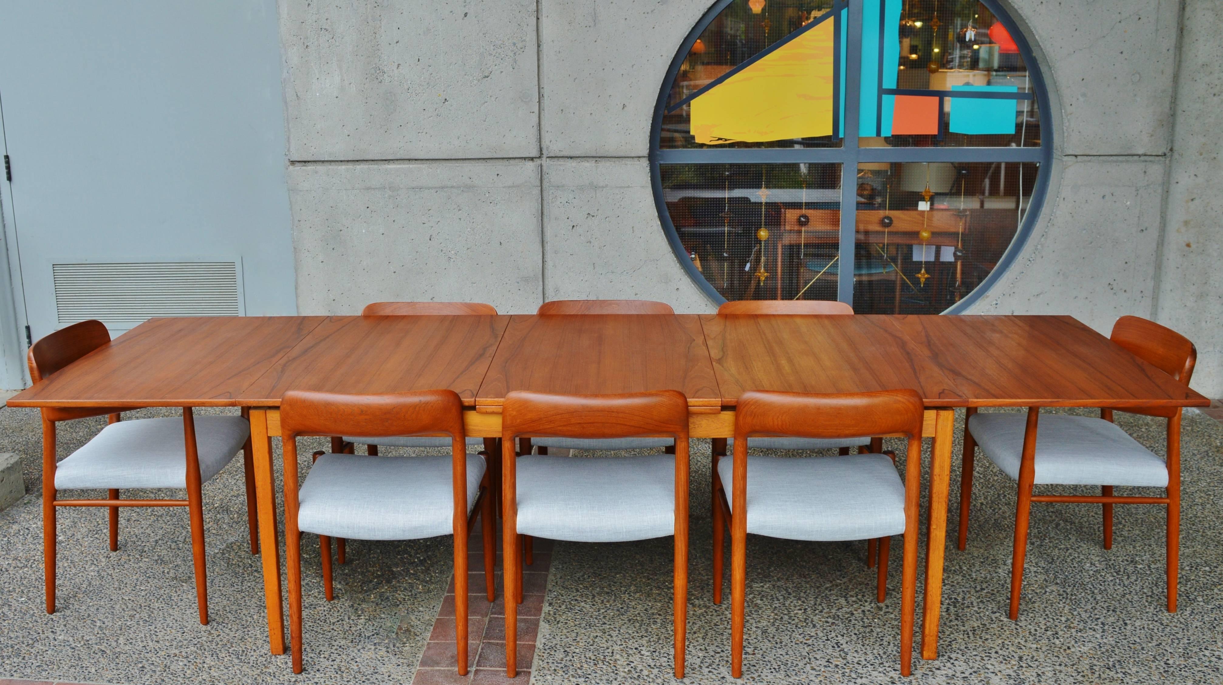 This amazing, top quality Danish Modern teak dining table has two huge flip open leaves that expand the table from seating six or eight people, to seating up to 12! Cleverly designed, the large leaves pullout and two risers pop up to raise the table
