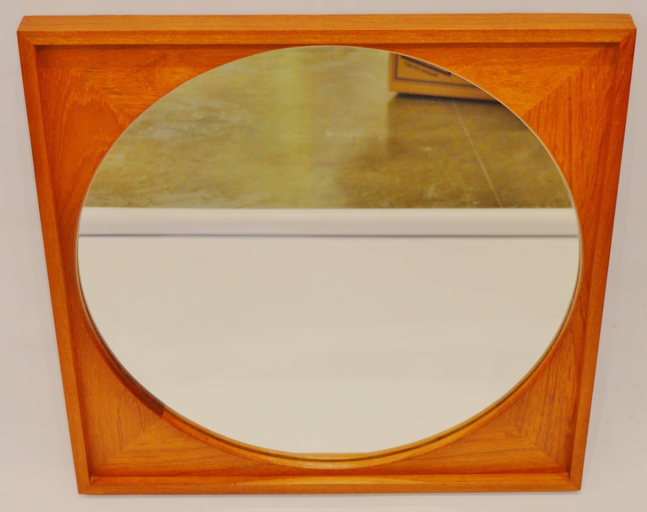 This lovely and unique Danish modern teak framed mirror has pretty detailing throughout. Featuring a thick edge that sits proud forward of the interior, mitred wood joinery on the face and a softly contoured rounded cut-away to reveal the mirror.