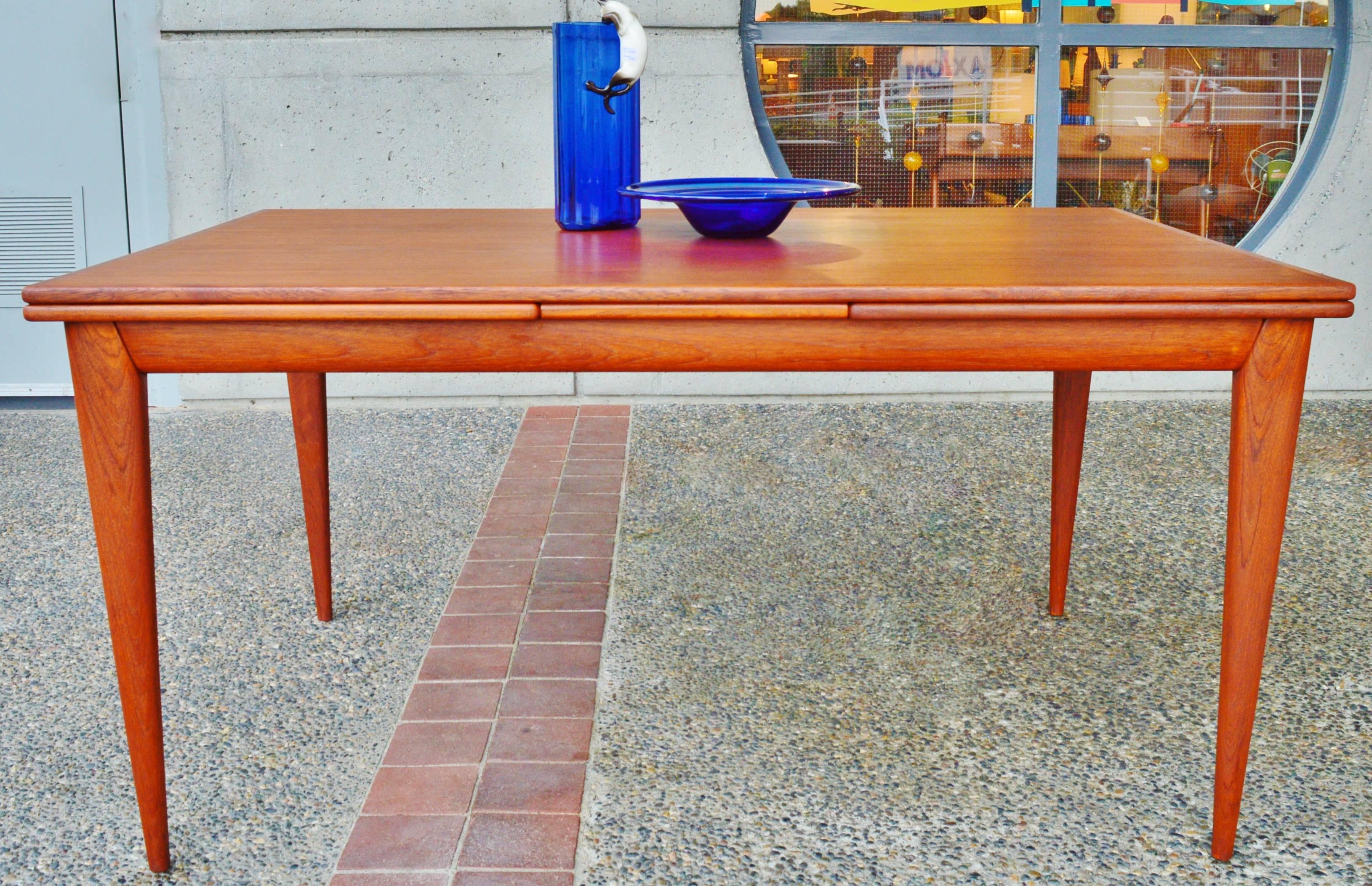 This impeccable and rare Danish Modern teak dining table or writing table was designed by Niels Otto Moller for J.L. Moller in the 1950s and is top quality construction throughout. One of the most awesome aspects is the stunning, solid teak
