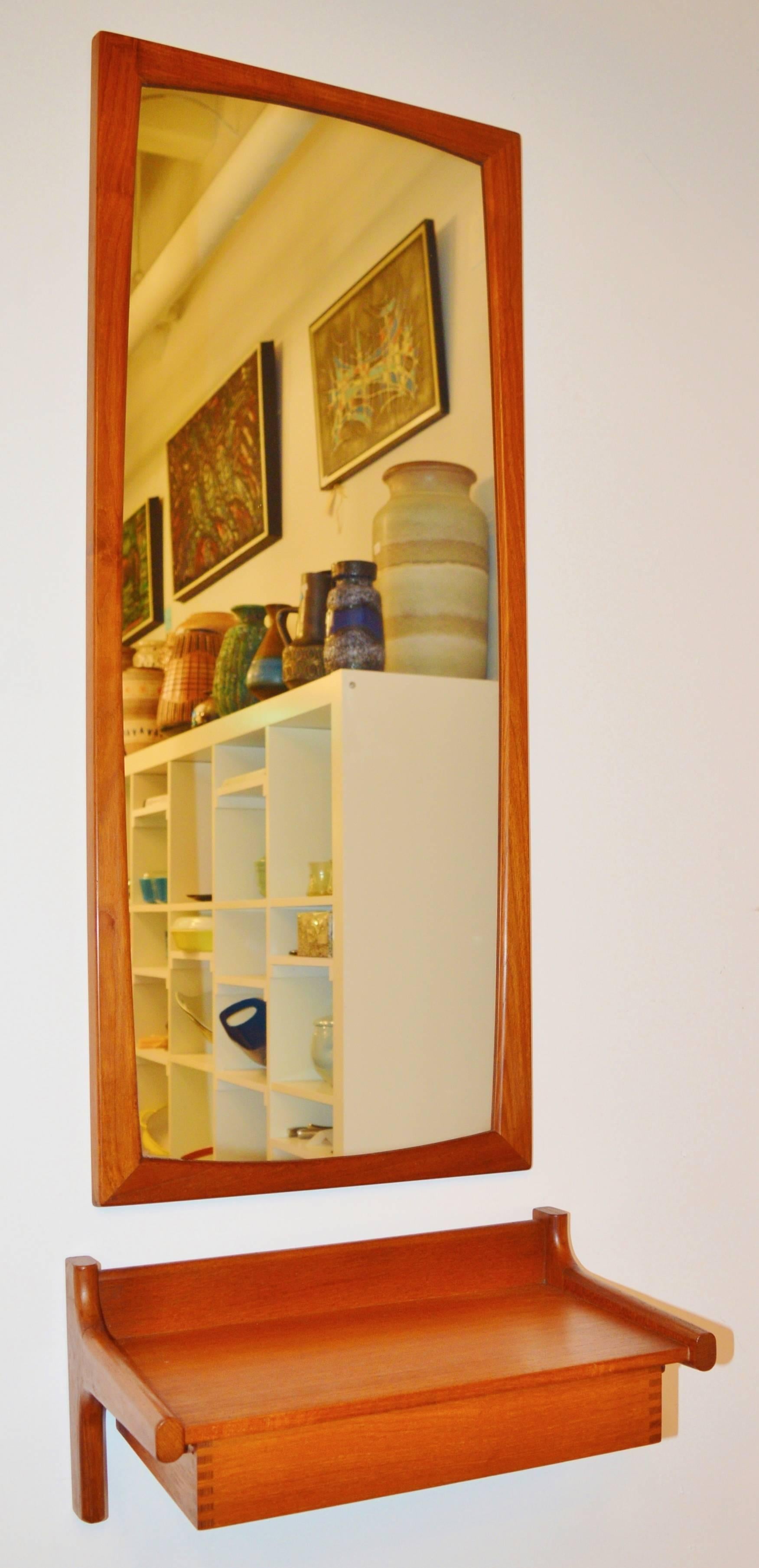 This is a lovely quality pairing of a Classic teak entry mirror to check yourself on the way out the door and a shelf with a drawer for your mail or keys. The mirror was designed by Aksel Kjersgaard and has gorgeous rounded corners and is strung to