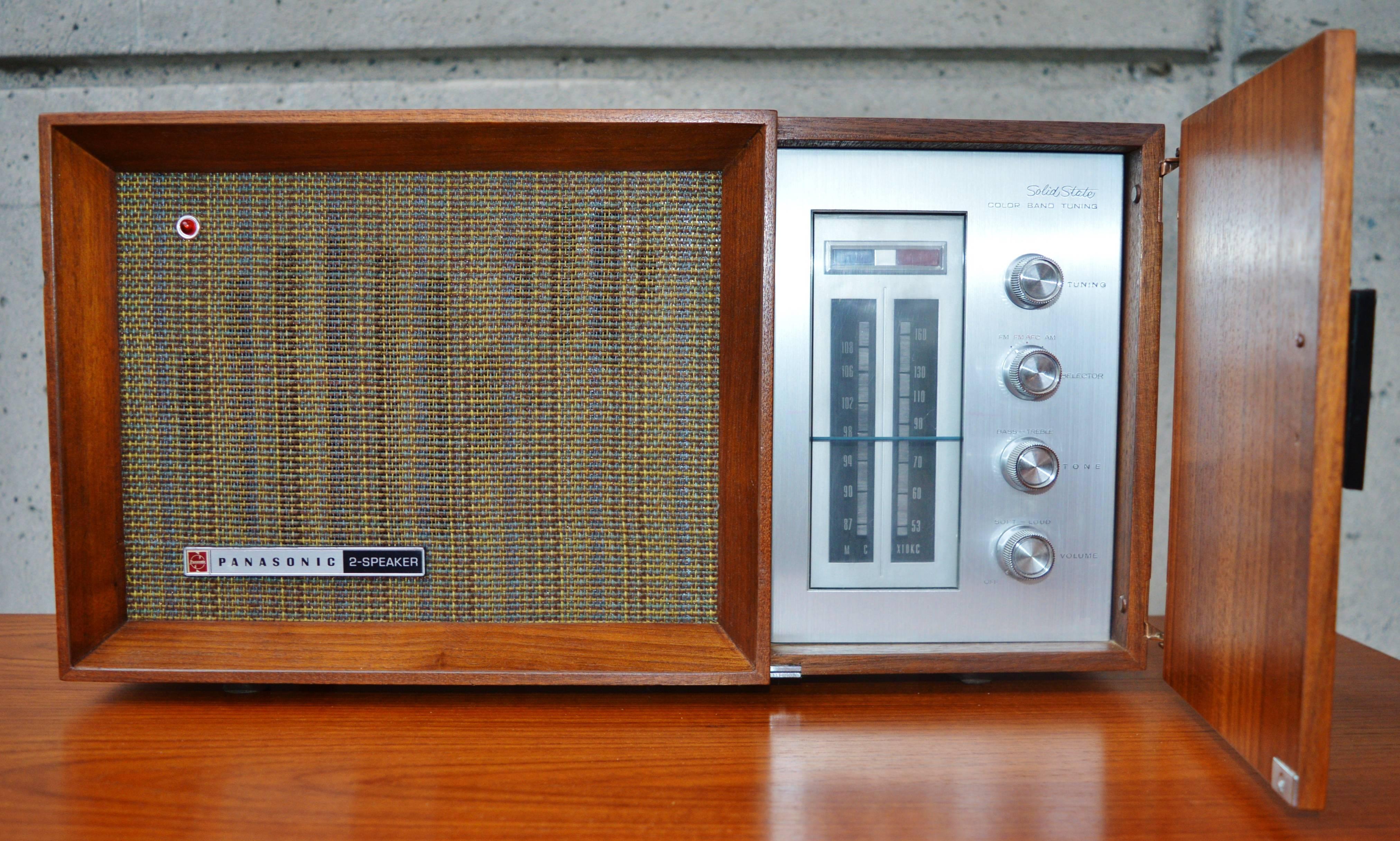 This super cool Mid-Century Modern Panasonic RE-7487 AM/FM radio is a rare model where the controls are hidden behind a door and so it is a lovely looking cabinet with the controls out of sight. Featuring a teak cabinet, with a hinged door that