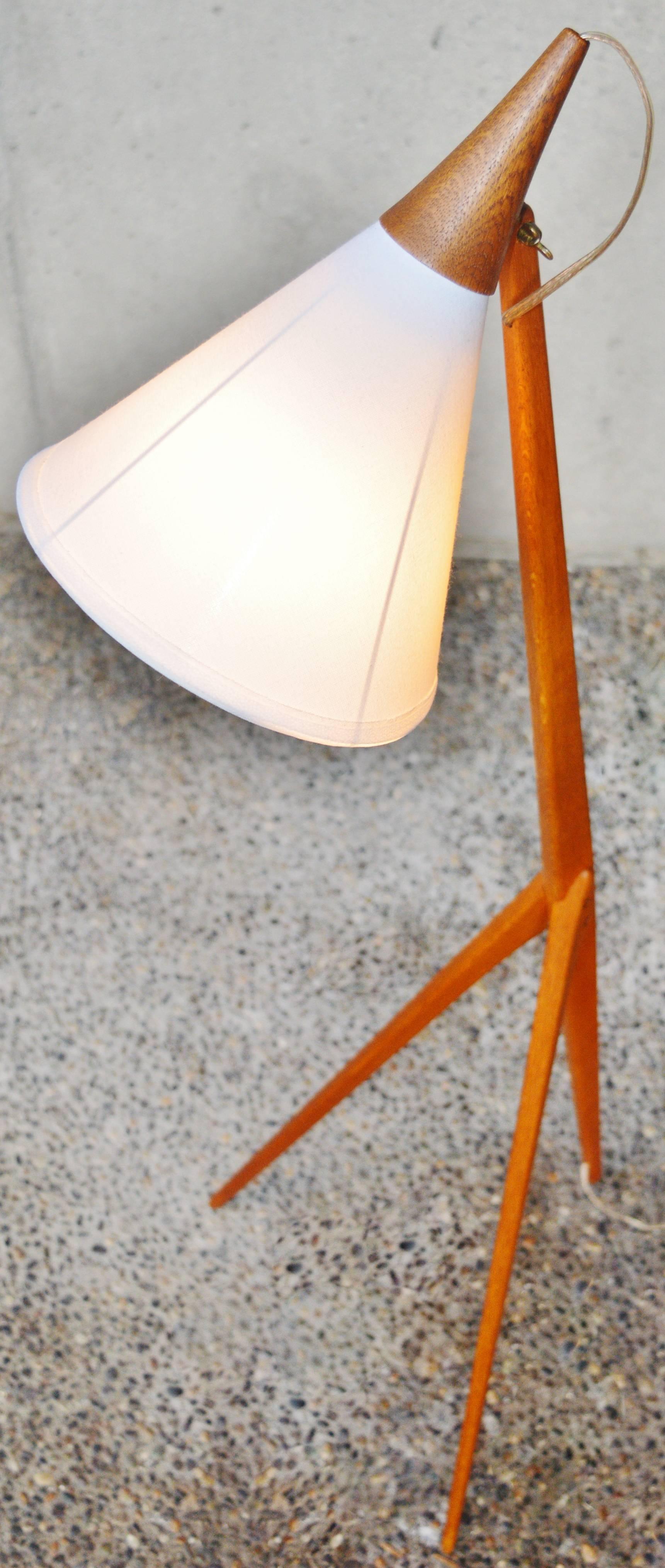 This gorgeous stand out Danish modern teak tripod lamp was designed by Uno Kristiansson for Luxus of Sweden in the 1960s. Featuring beautifully contoured teak legs that meld into the main stem. The teak conical cap becomes an extension of the new