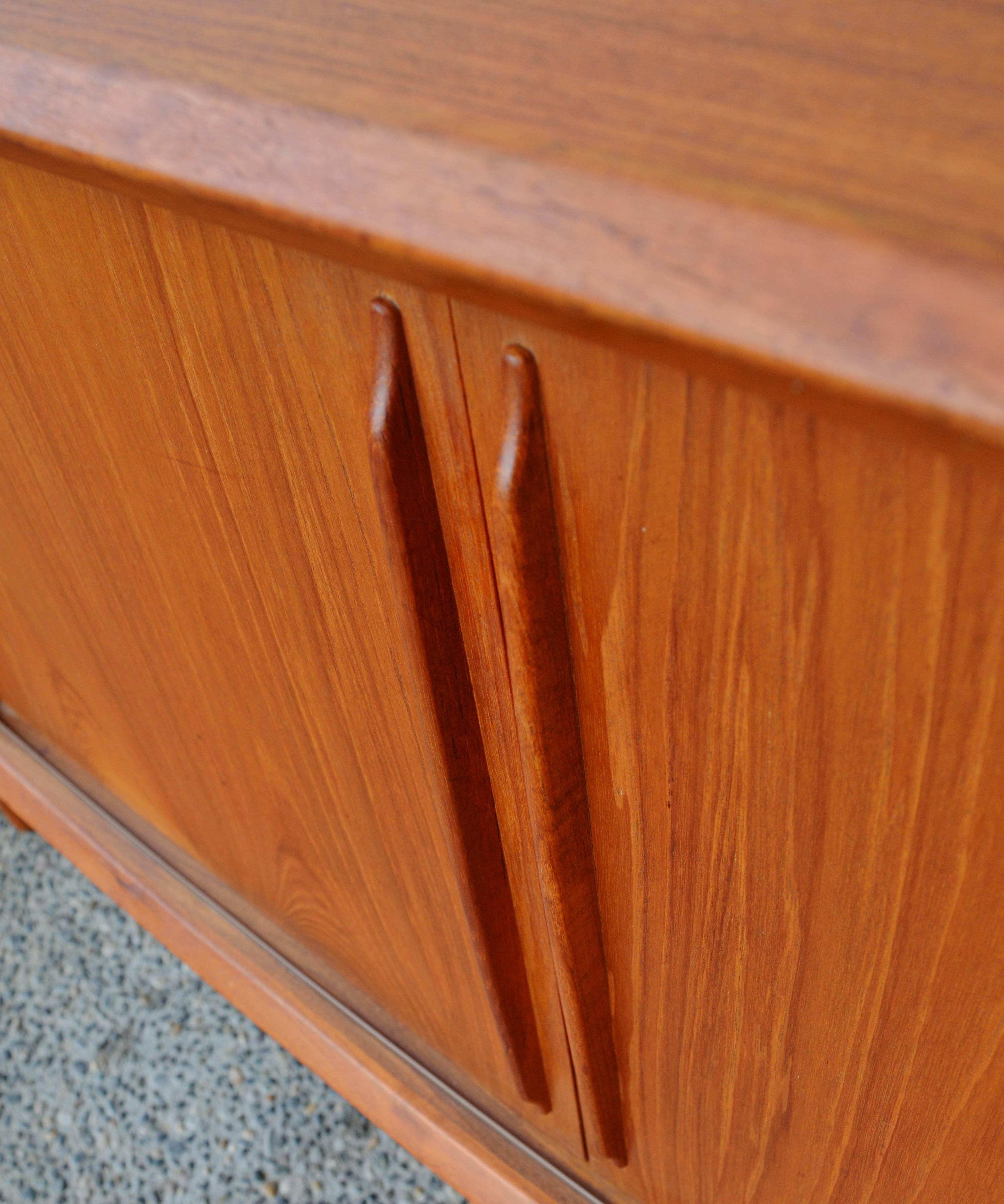 This elegant Danish Modern teak credenza or buffet by Arne Vodder for H.P. Hansen has gorgeous, classical lines with it's beautiful arced bow-front and substantial tapering, conical legs. The 4 sliding doors have sculpted elongated door pulls, and