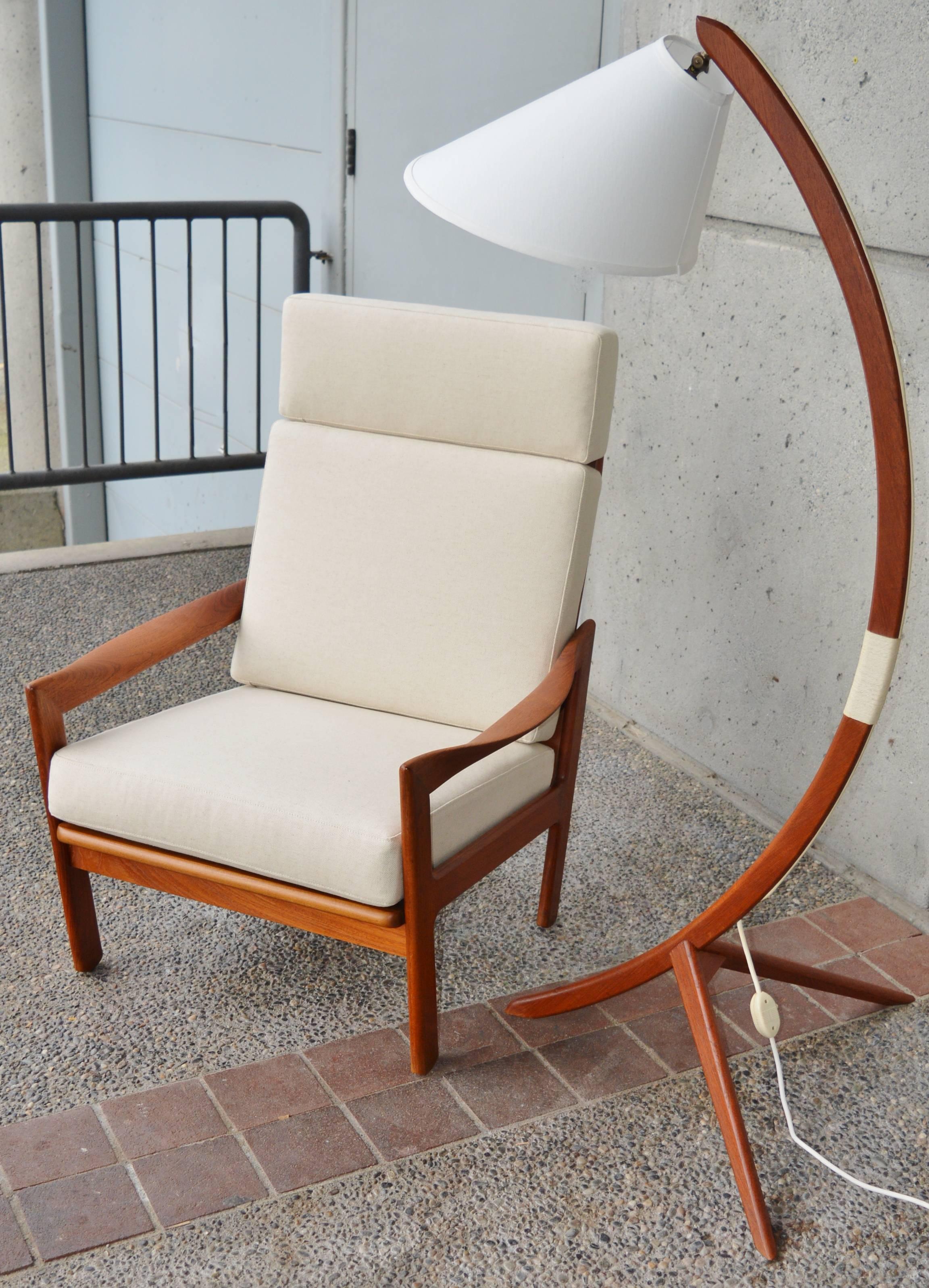 This gorgeous and rare Danish Modern teak frame restored lounge chair was designed by Illum Wikkelso for Niels Eilersen. Featuring ultra deep curved and flared arm rests, legs that tip toward the center and a tall back with sultry vertical back