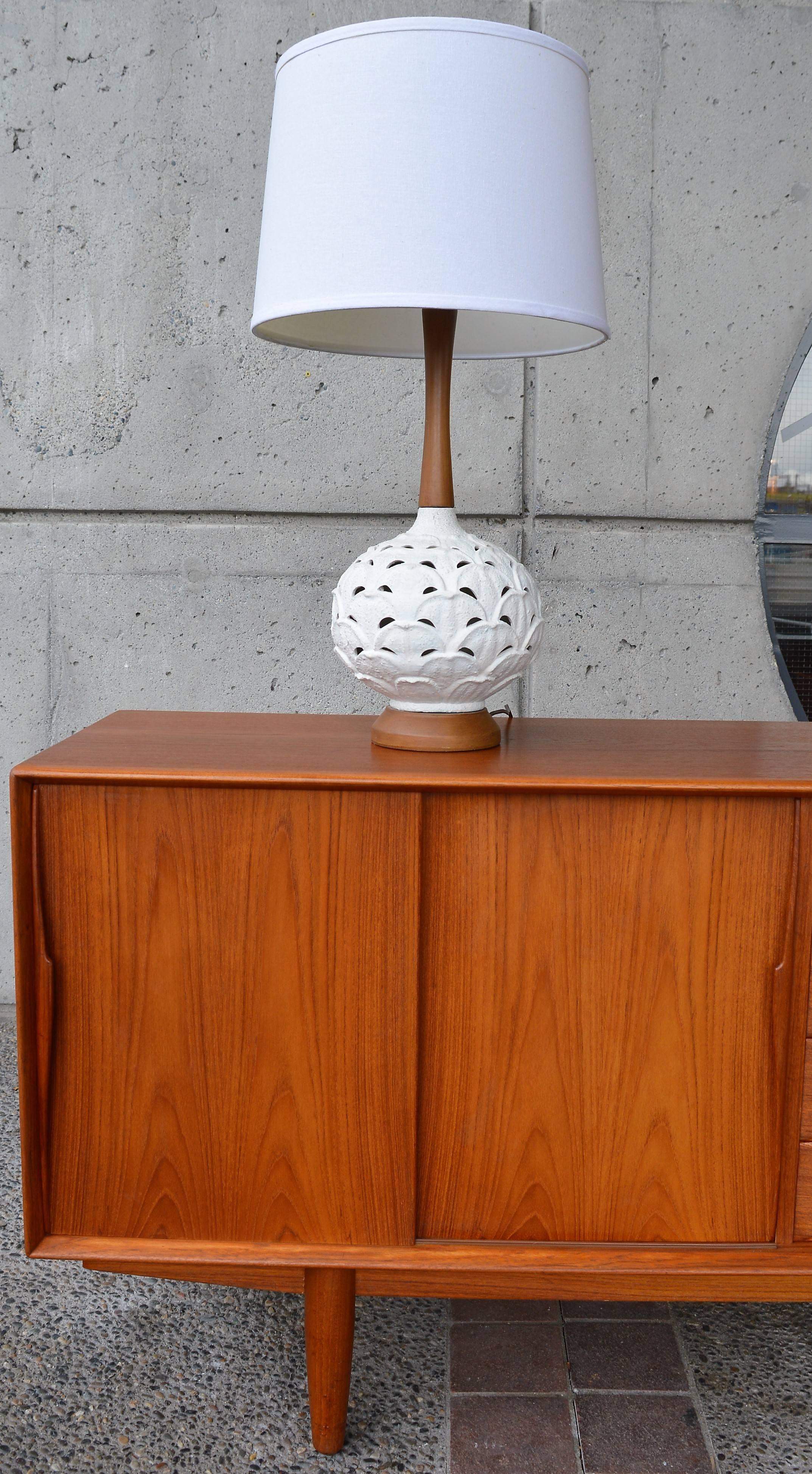 This lovely Mid-Century Modern white ceramic lamp has a wonderful scalloped petal design with airy cutaways. Featuring a sculptural solid walnut base and stem and in fantastic condition. Please note the lamp comes with the brass harp and finial, but