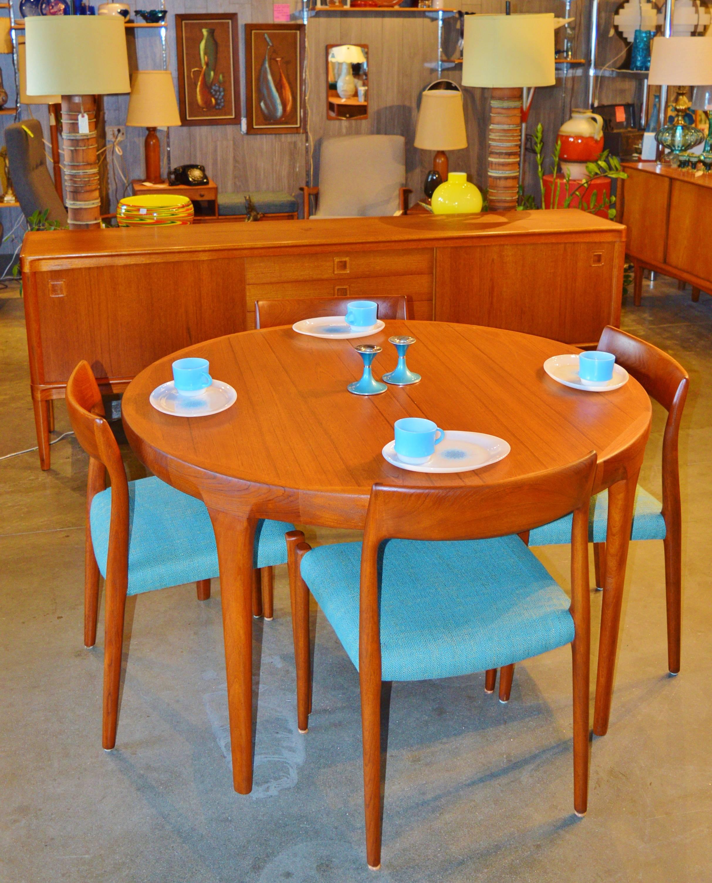 This absolutely stunning Danish Modern teak dining table was designed by Ib Kofod Larsen for Faarup Møbelfabrik in the 1950s. Featuring a gorgeous thick top that contours and blends with the tapering legs. Super practical, it starts as a round table
