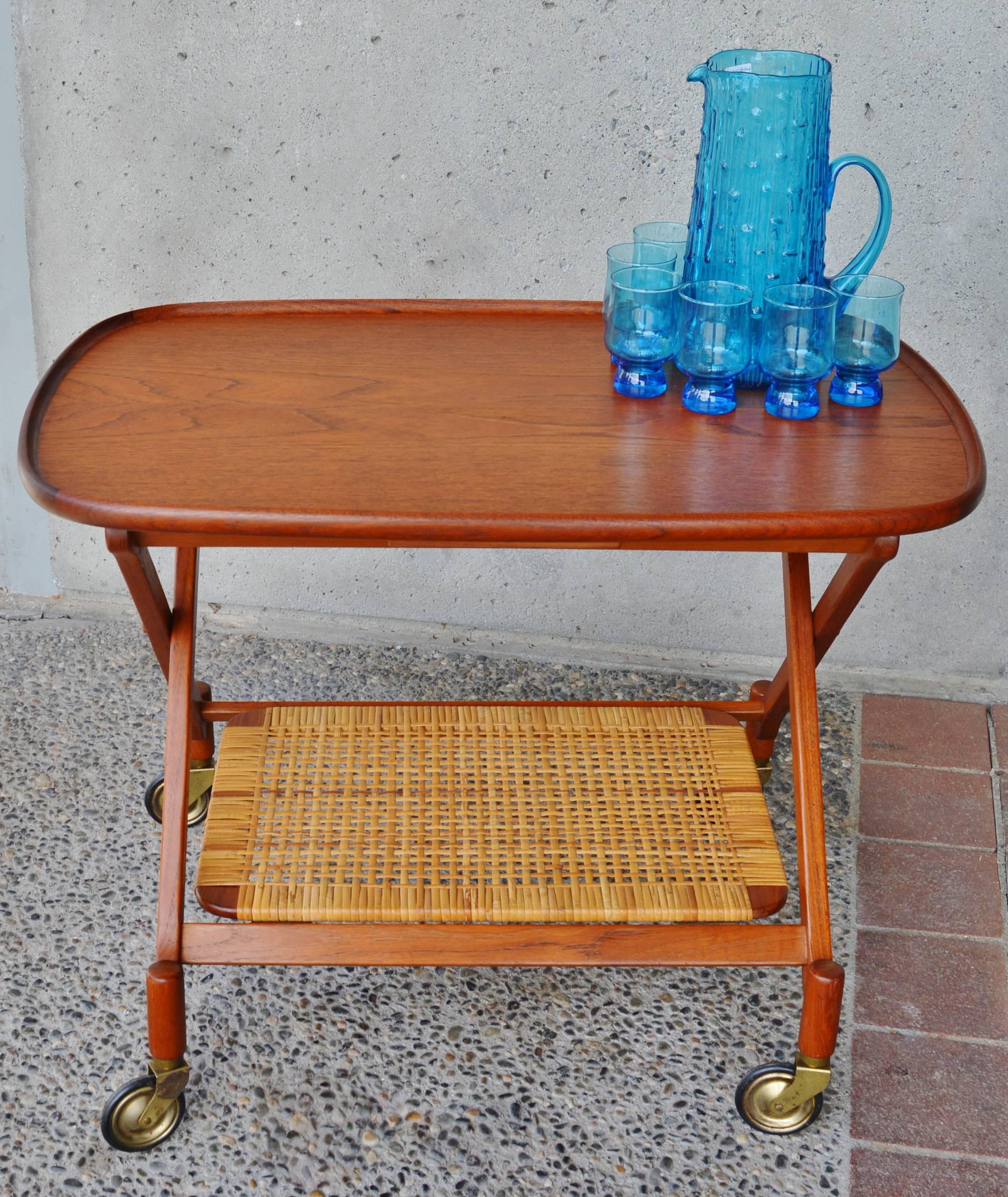 This gorgeous Danish modern quality teak bar cart has impeccable detailing throughout! The ovoid top has a lovely flared lip, the scissor legs are dramatic and the conical leg extensions above the Classic 1950s casters are amazing! Finally, the