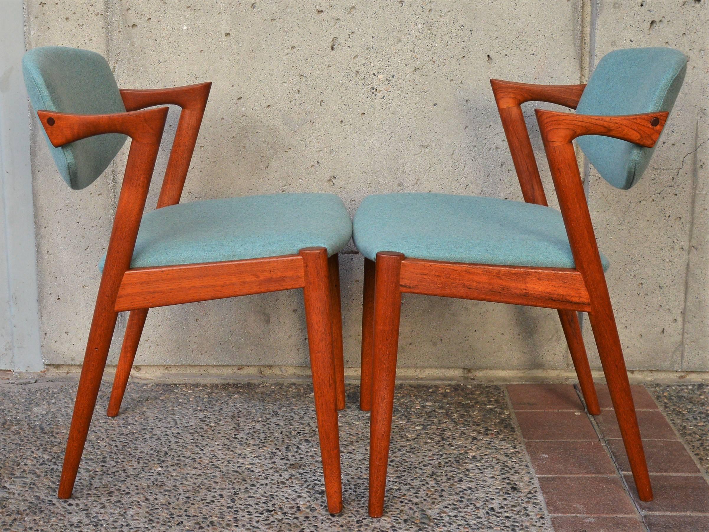 This incredible set of eight Danish Modern teak dining chairs were designed by Kai Kristiansen in the 1960s. Featuring gorgeous sculptural lines, such as the angled, truncated armrests, and the inwardly splayed back legs. The set has been reglued,