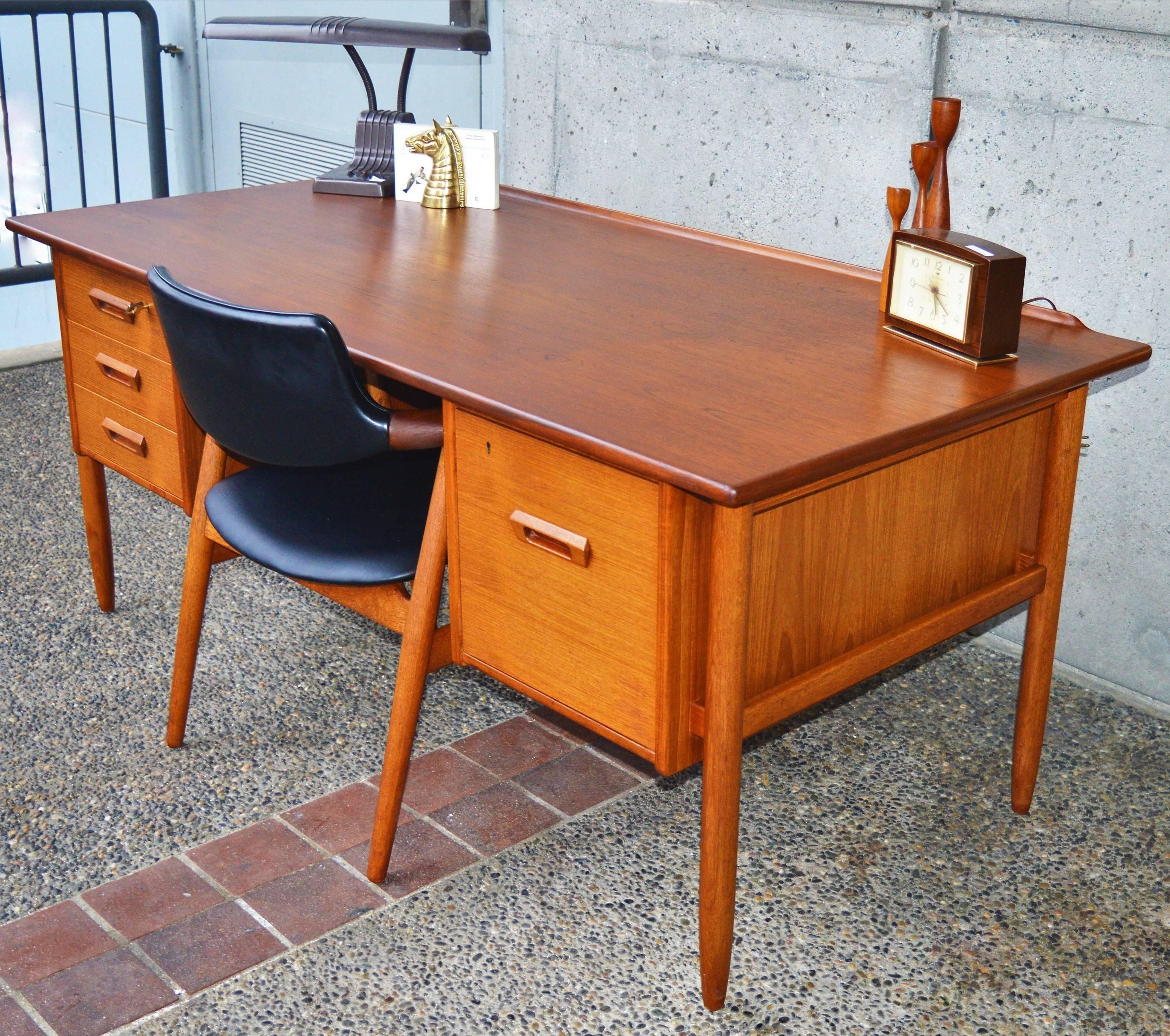 This gorgeous Danish modern quality teak desk was designed by Goran Strand for Lelangs Mobelfabrik, 1960s. Featuring a stellar curved lip at the back of the desk, floating leg braces, and a back display shelf with locking bar. This is the much rarer