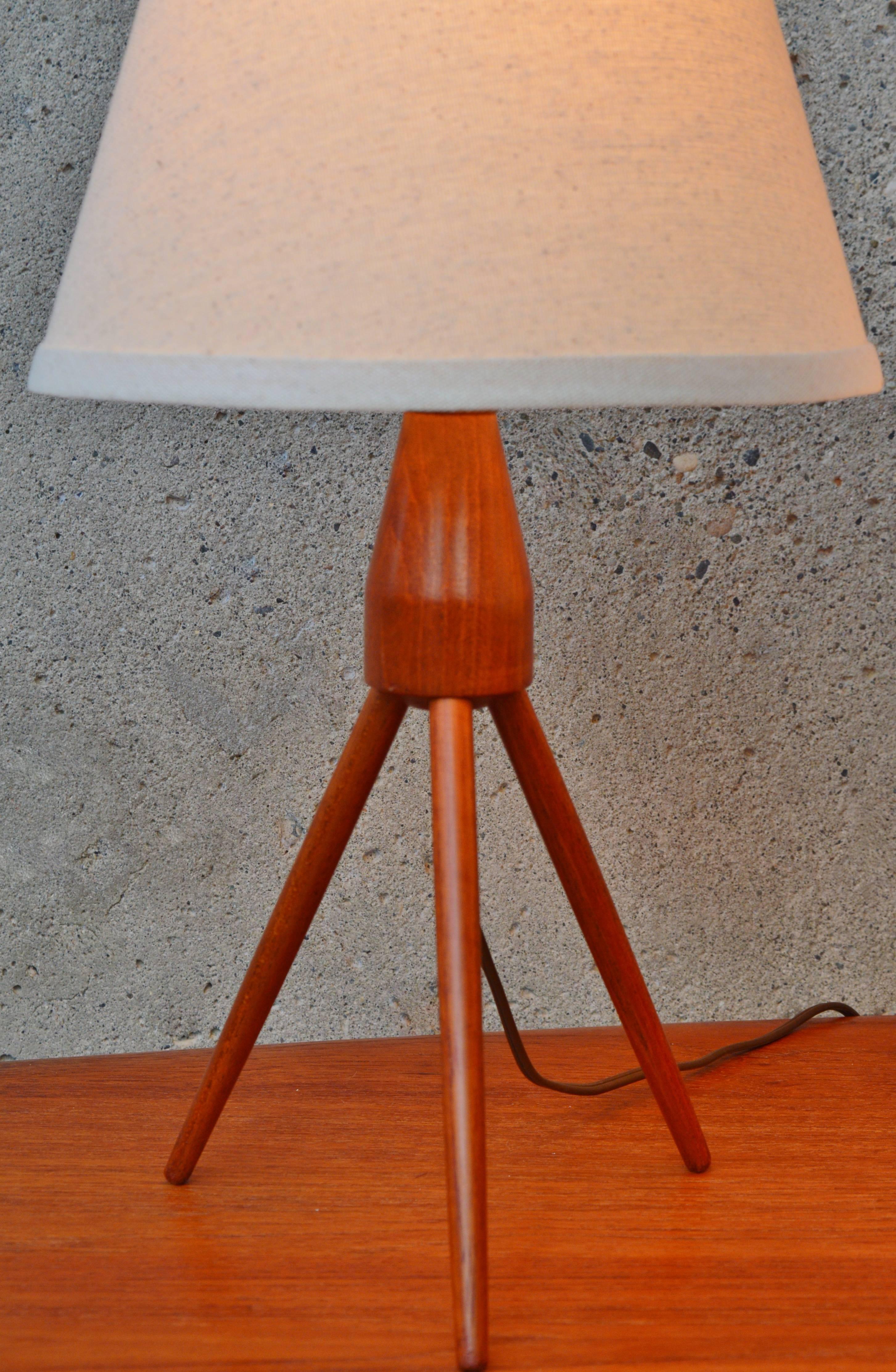 These delightful Danish Modern Atomic Era style tripod rocket table lamps are super fun! Featuring a contoured main teak stem with three tapering legs and matching cream linen clip on shades. Both in fantastic vintage condition; wired for North