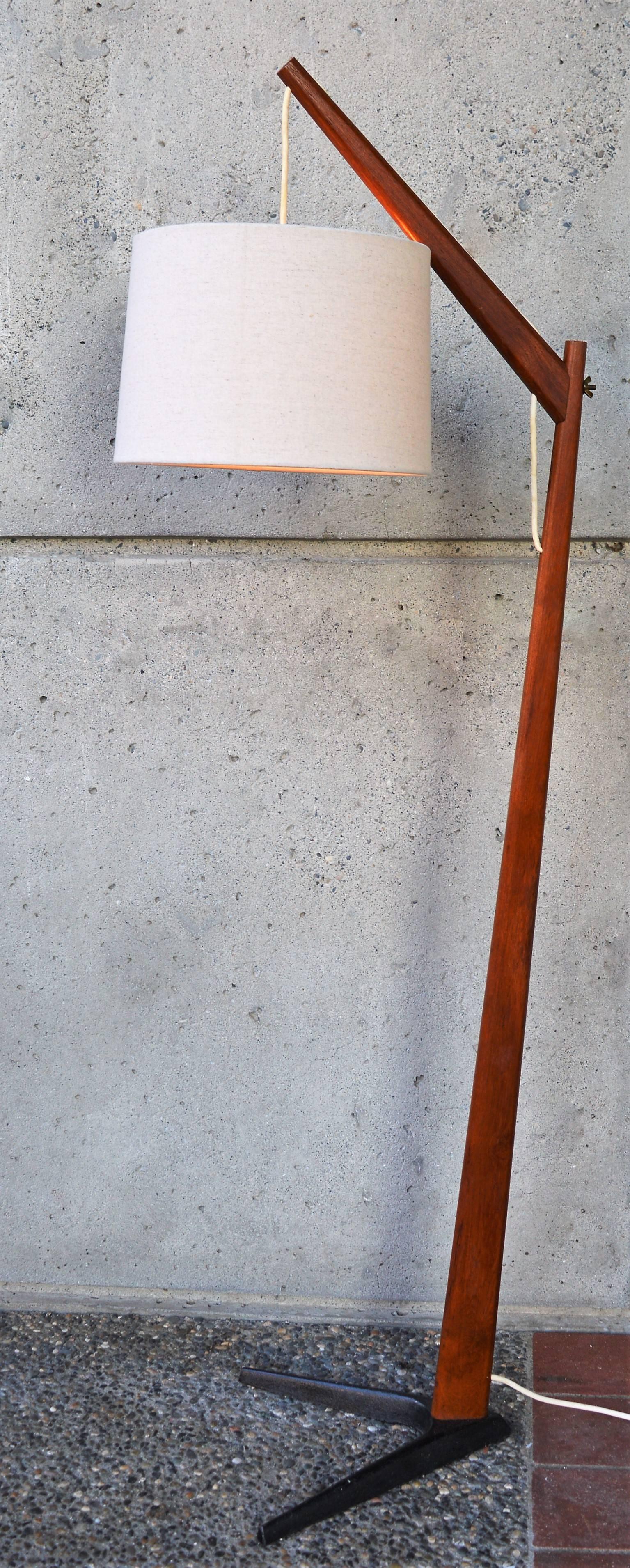 This superb and rare 1950s Danish modern teak floor lamp is attributed to Svend Aage Holm Sorensen. Featuring his iconic V-shaped iron base, a thick solid teak stem that tapers gently as it reaches the top where it connects to the teak arm
